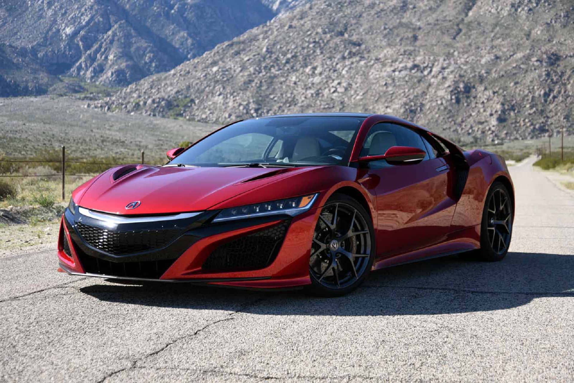 Acura 桌布 壁紙 — 一輛亮麗的紅色跑車停在龜裂的柏油路上，背景是崎嶇的山脈，在明亮的日光下。