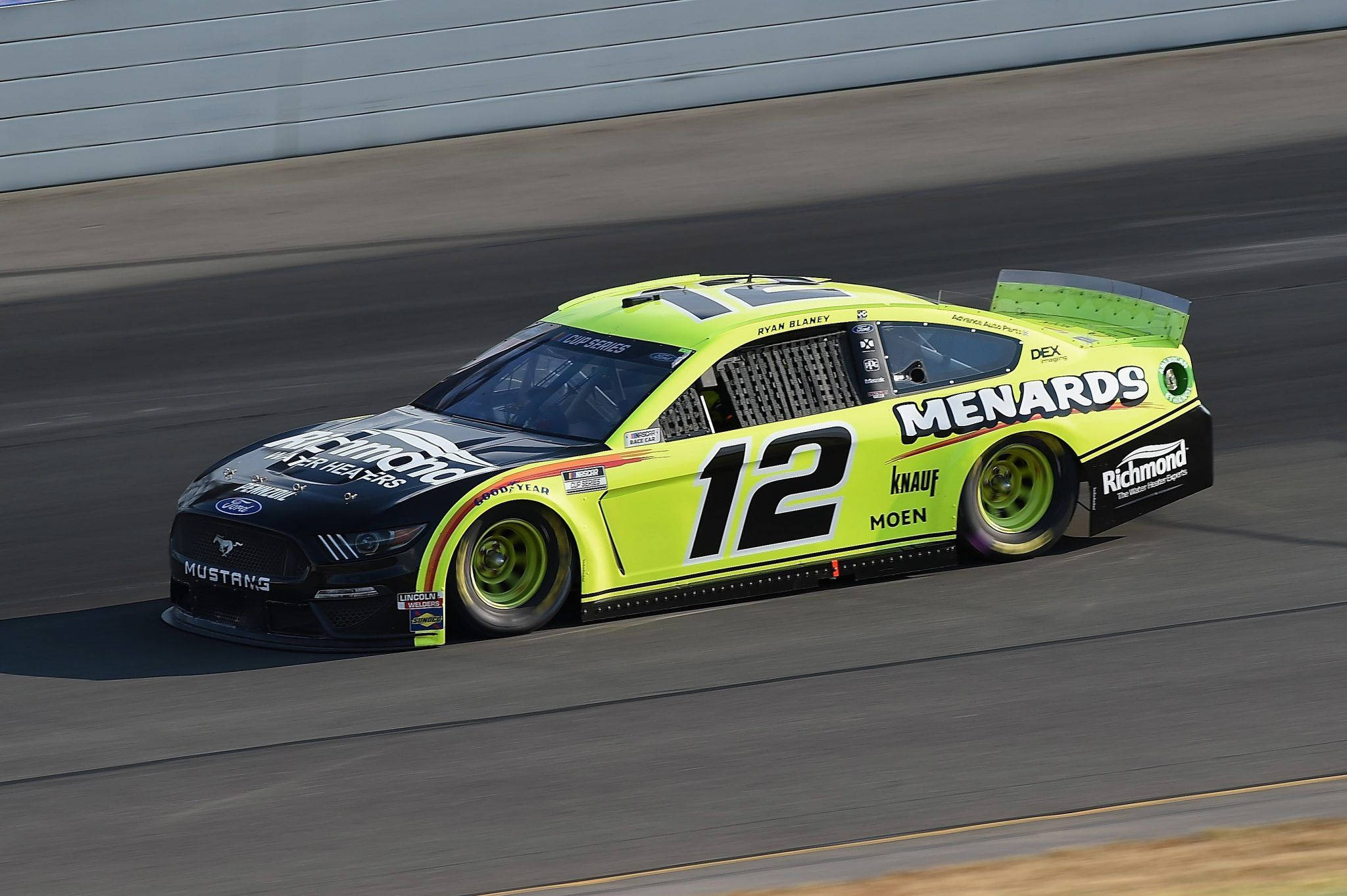 Ryan Blaney 桌布 壁紙 — 一輛亮麗的萊姆綠和黑色NASCAR賽車（編號12）在晴朗的日光下沿著賽道飛馳。