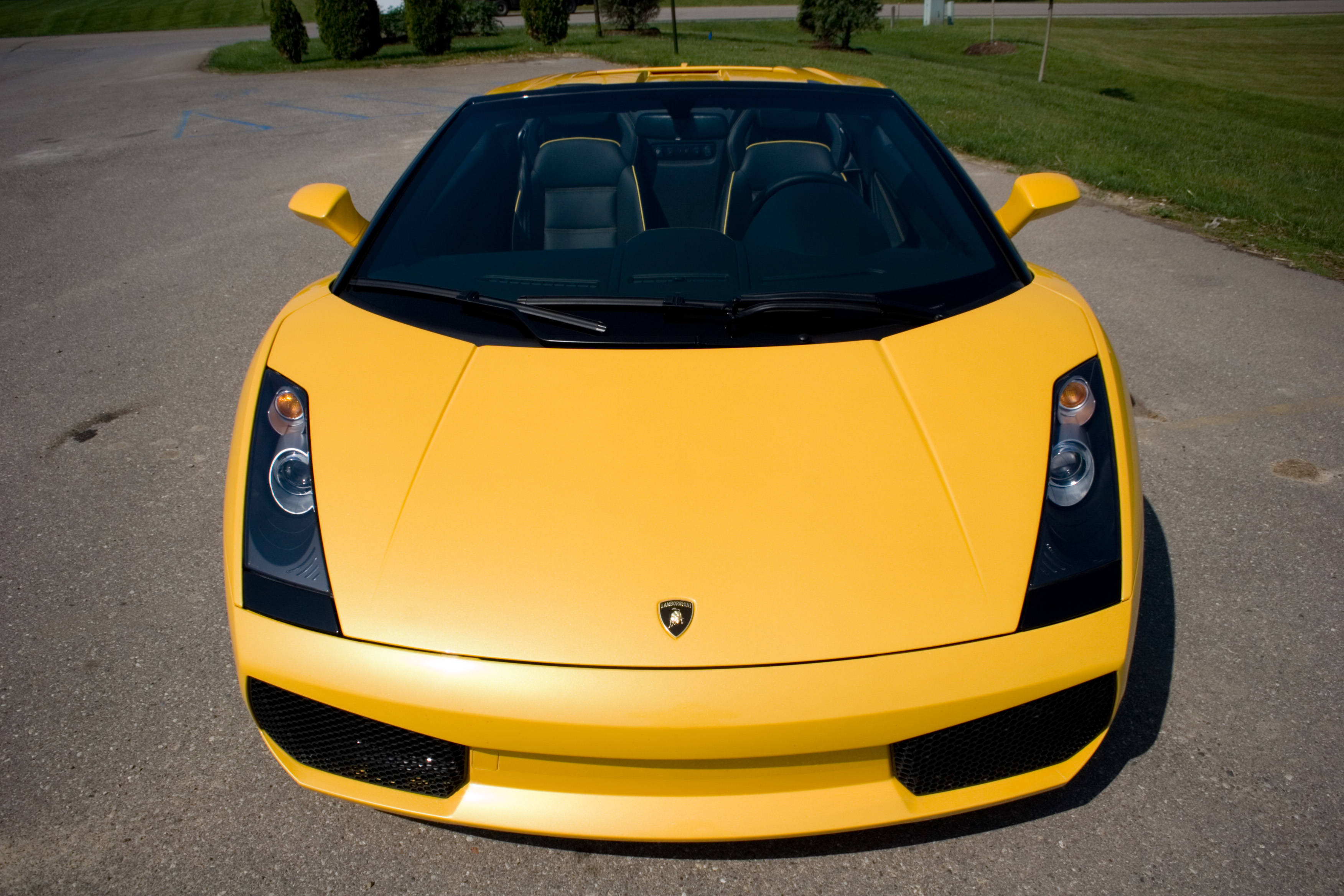 4K Lamborghini 桌布 壁紙 — 一輛亮黃色Lamborghini跑車，帶有黑色飾邊，停在瀝青停車場，在晴朗的日光下。