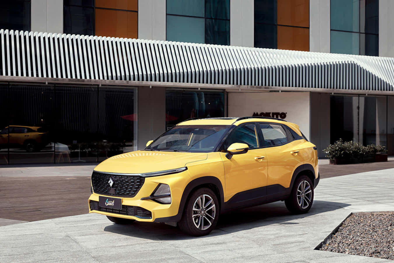 Baojun 桌布 壁紙 — 一輛亮黃色SUV停放在現代瓷磚廣場上，前方是時尚的玻璃建築，帶有條紋遮陽篷。
