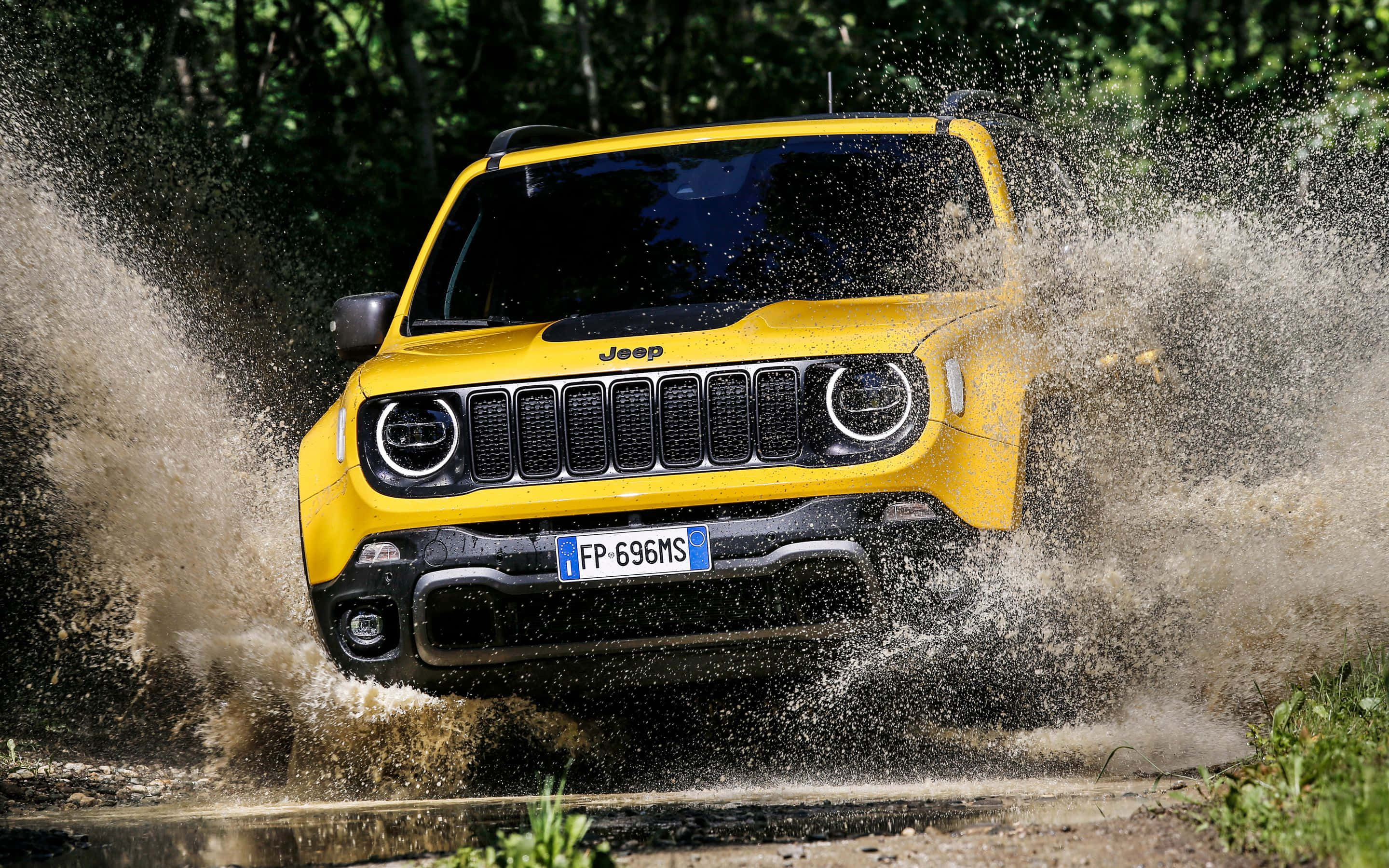 Jeep Renegade 桌布 壁紙 — 一輛亮黃色的Jeep Renegade在茂密翠綠的森林中濺起泥濘水花。