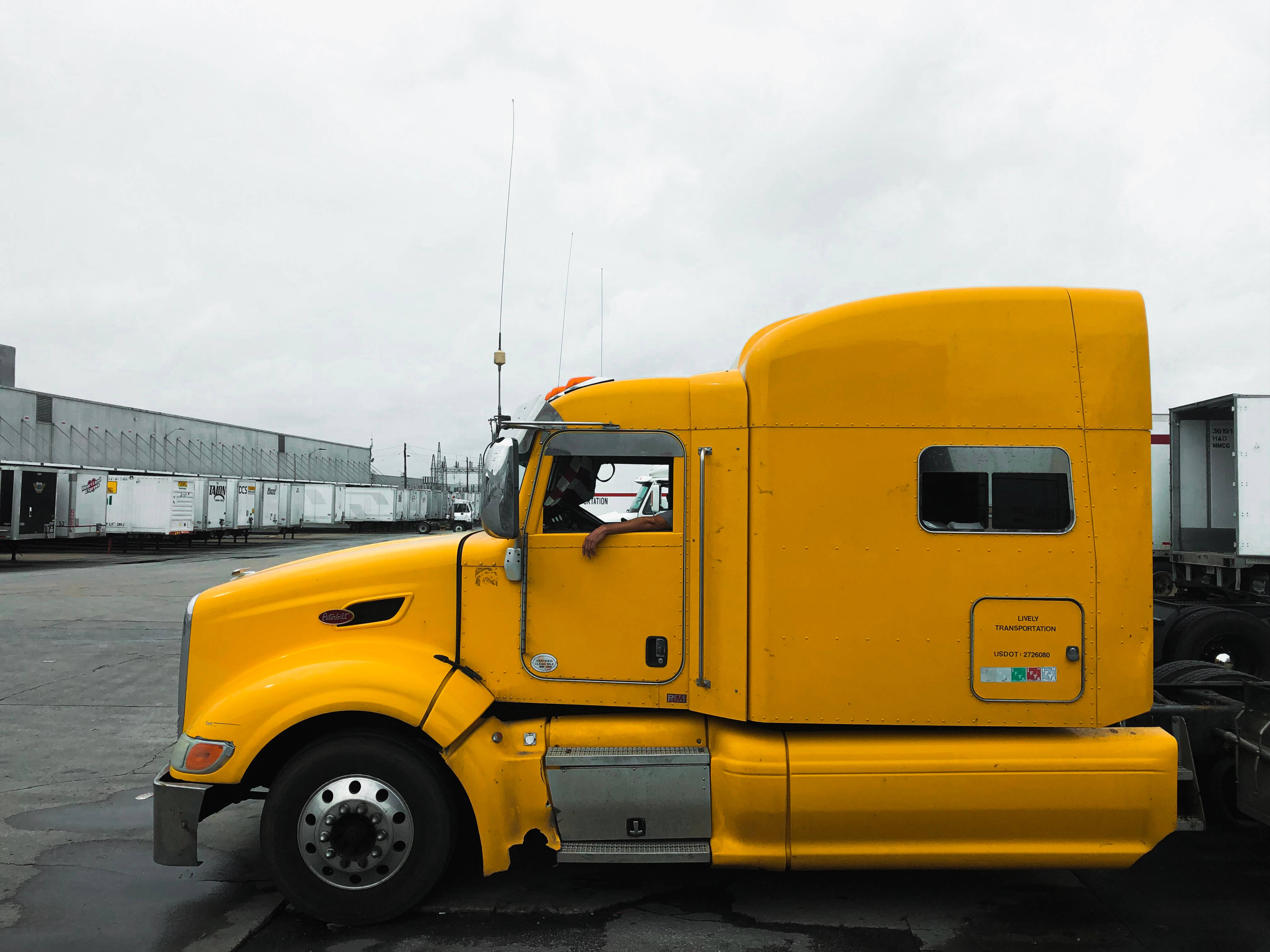 Truck 桌布 壁紙 — 一輛亮黃色的半掛卡車駕駛室停放在貨運場，天空多雲，背景中拖車排成一排。