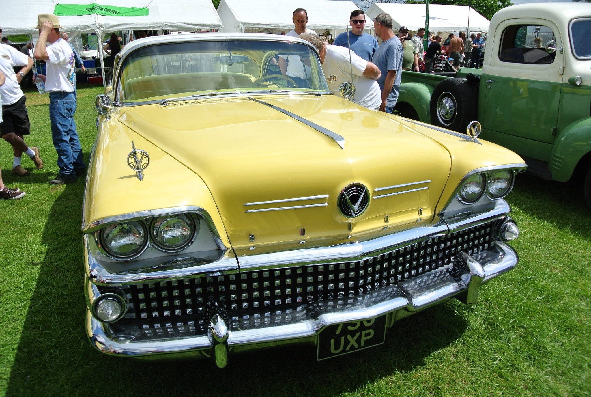 Buick 桌布 壁紙 — 一輛亮黃色的復古車帶有鍍鉻細節，在戶外經典車展的陽光草地上閃閃發光。