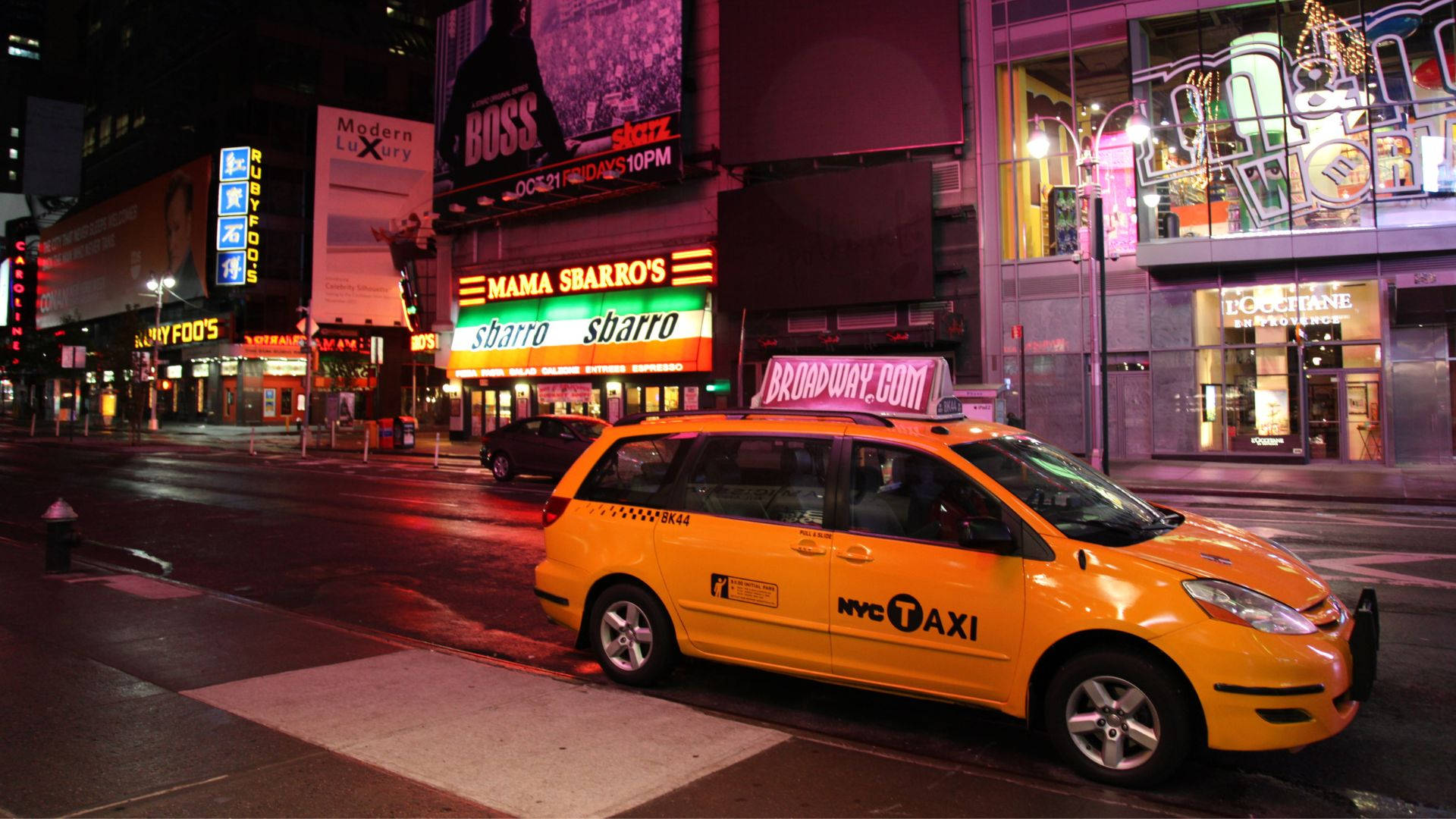 taxi 桌布 壁紙 — 一輛亮黃色的紐約計程車在夜晚停泊在濕漉漉的城市街道上，周圍是閃爍的霓虹燈招牌和明亮的商店櫥窗。