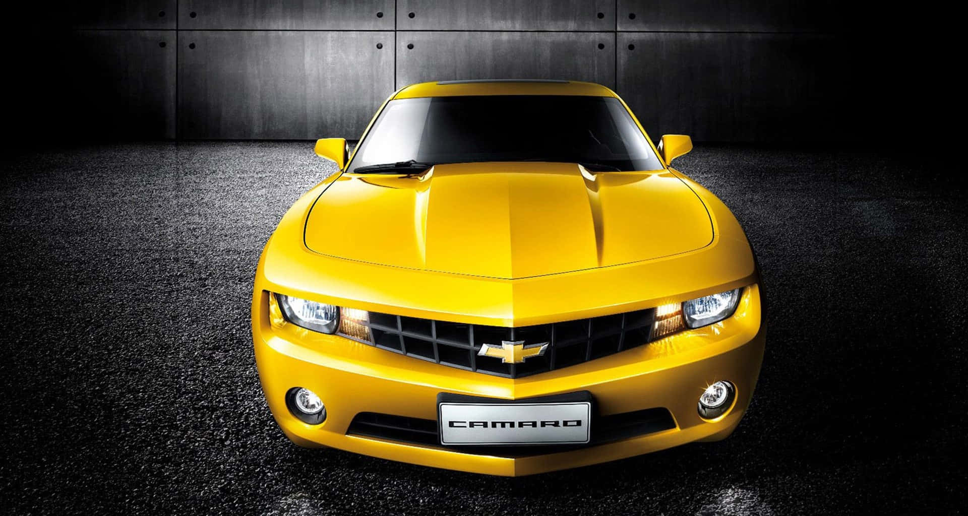 Yellow Car 桌布 壁紙 — 一輛亮黃色的雪佛蘭科邁羅跑車在攝影棚燈光下，映襯著深色紋理牆壁和地板閃閃發光。