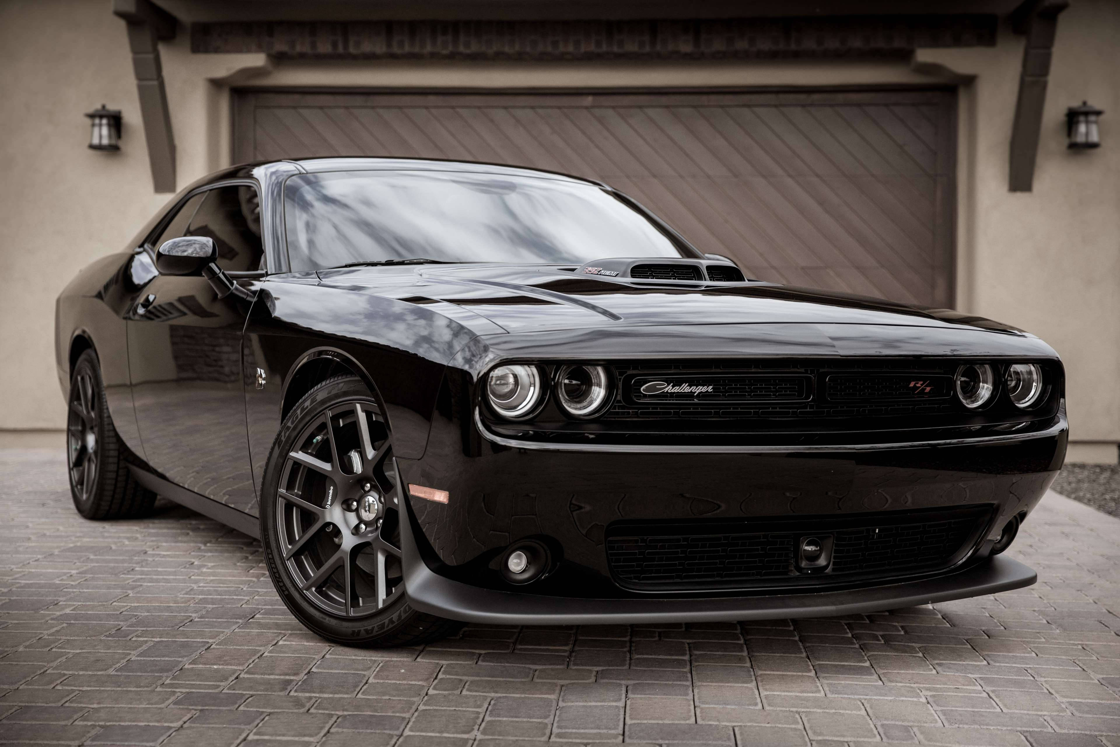 Challenger 桌布 壁紙 — 一輛亮黑色Dodge Challenger SRT停放在車庫前的石頭車道上，車庫有溫暖的環境照明。