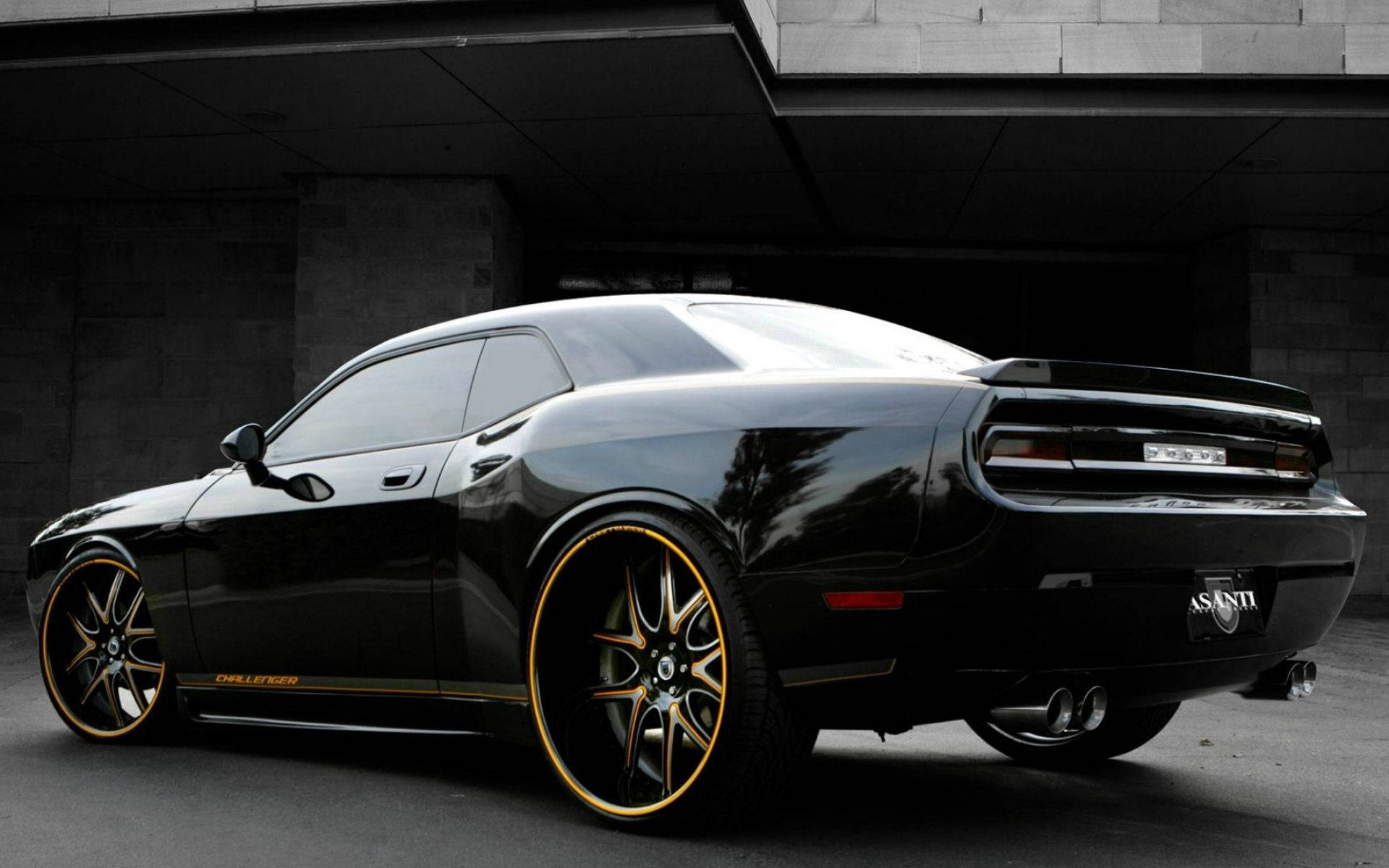 道奇隊 桌布 壁紙 — 一輛亮黑色Dodge Challenger配金色輪圈停放在混凝土簷篷下。