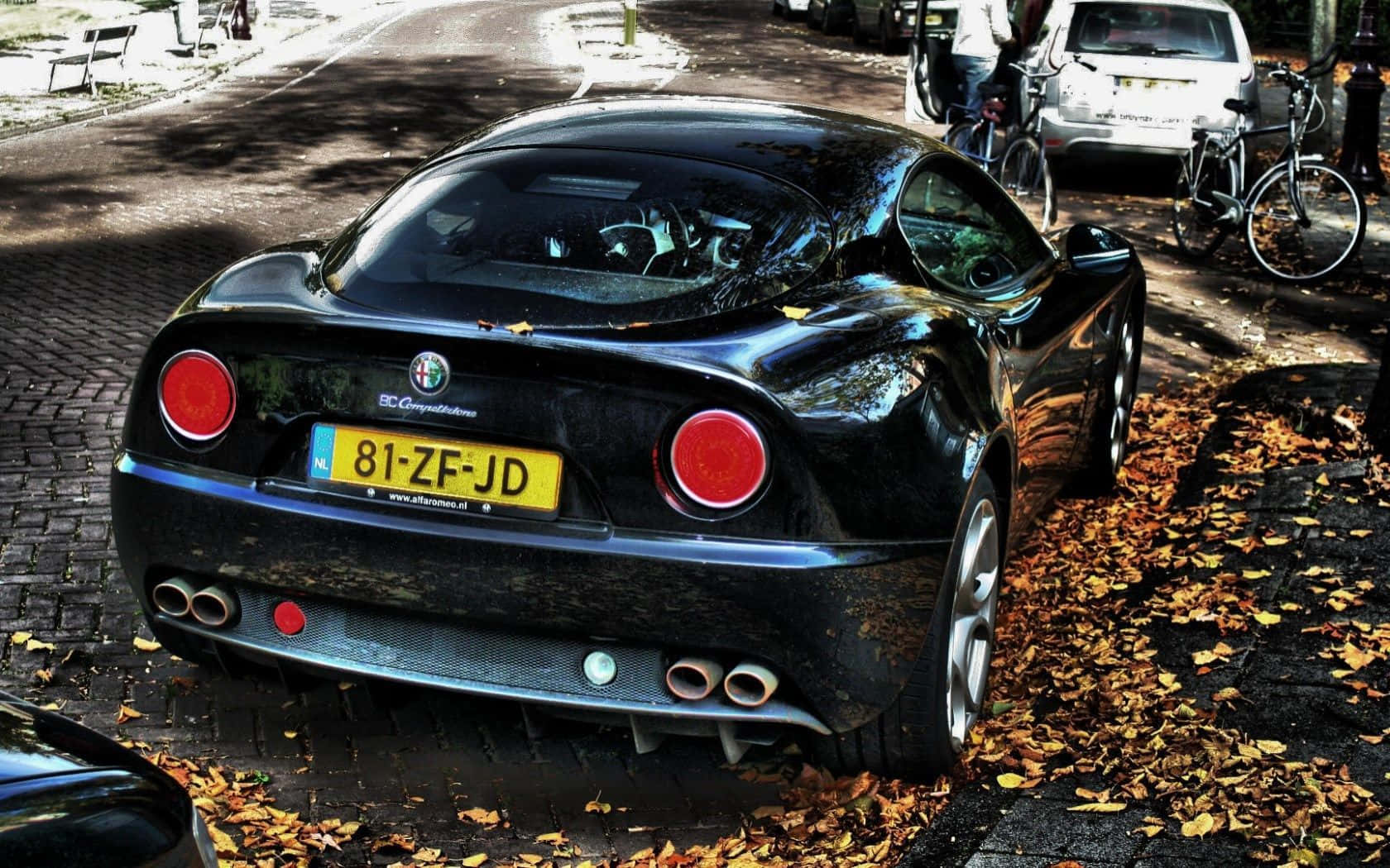 Alfa Romeo 8c Competizione 桌布 壁紙 — 一輛亮黑色的Alfa Romeo跑車停泊在散落著秋天落葉的鵝卵石街道上。