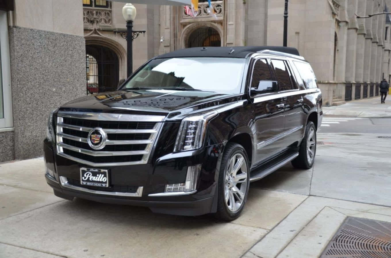 Cadillac Escalade 桌布 壁紙 — 一輛亮黑色的Cadillac Escalade在日光下停放在城市人行道旁華麗的石造建築旁。