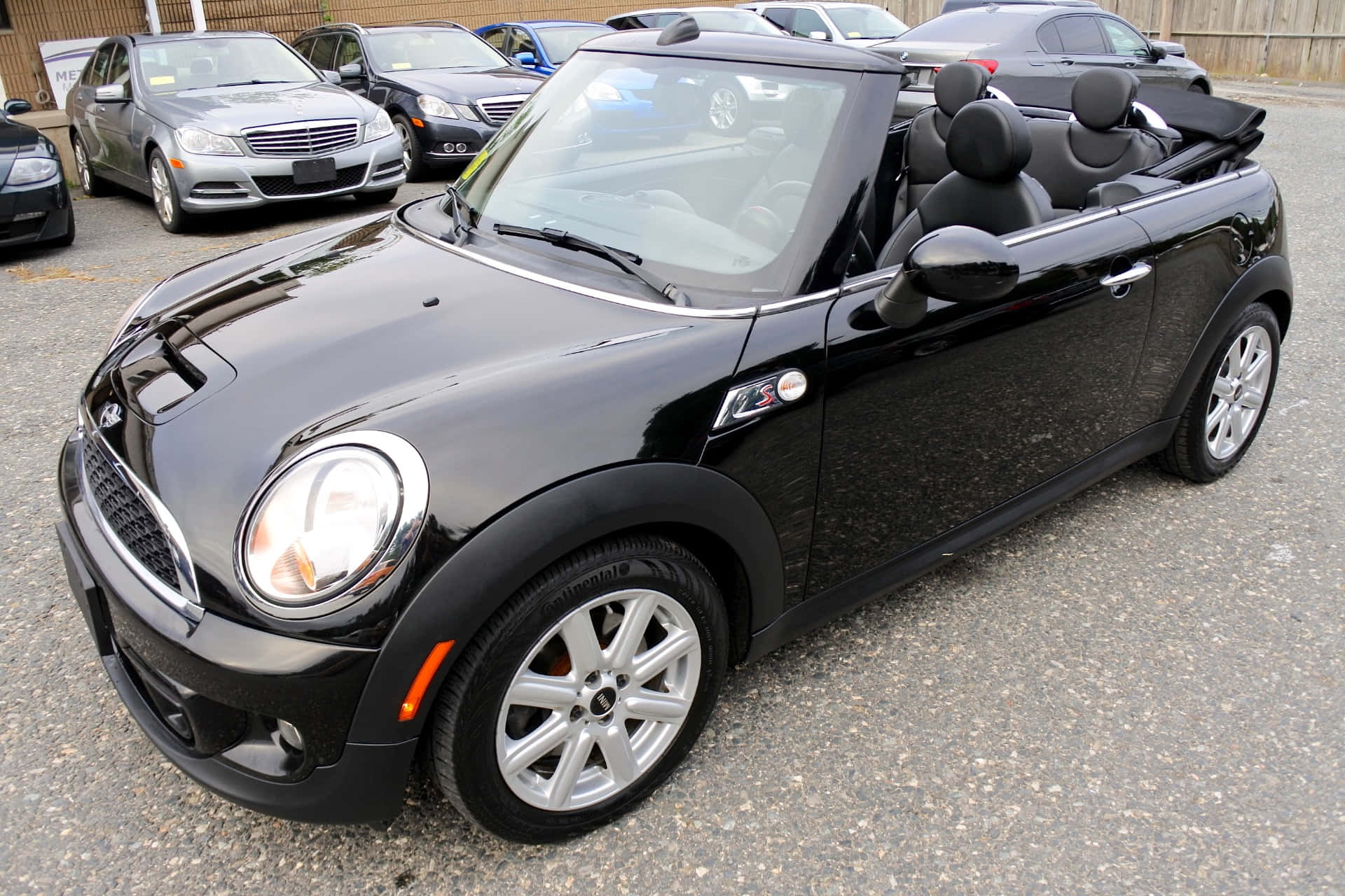 Mini Cooper S Convertible 桌布 壁紙 — 一輛亮黑色的Mini Cooper敞篷車停在碎石停車場，背景有其他車輛。