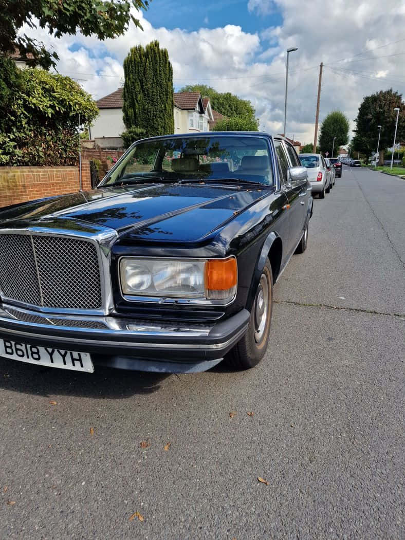 Bentley Eight 桌布 壁紙 — 一輛亮黑色賓利T系列轎車停泊在郊區街道上，天空局部多雲。
