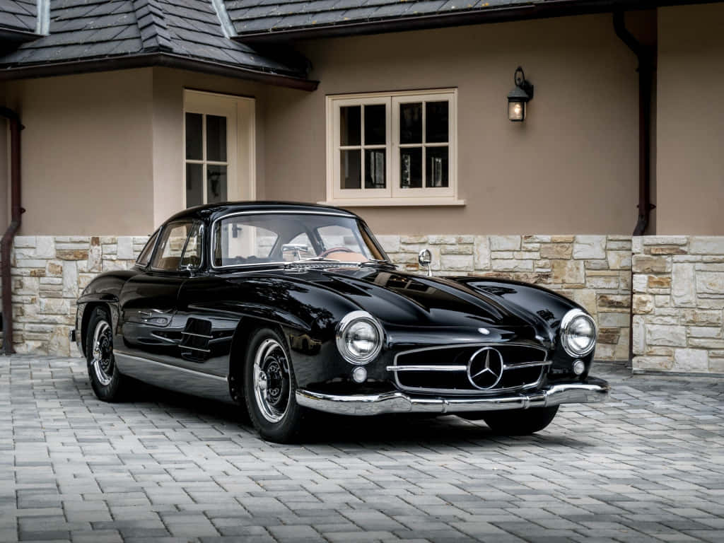 Classic Mercedes 桌布 壁紙 — 一輛亮黑色賓士300SL鷗翼停放在石砌車道上，前方是一棟米色搭配石材裝飾的房屋。