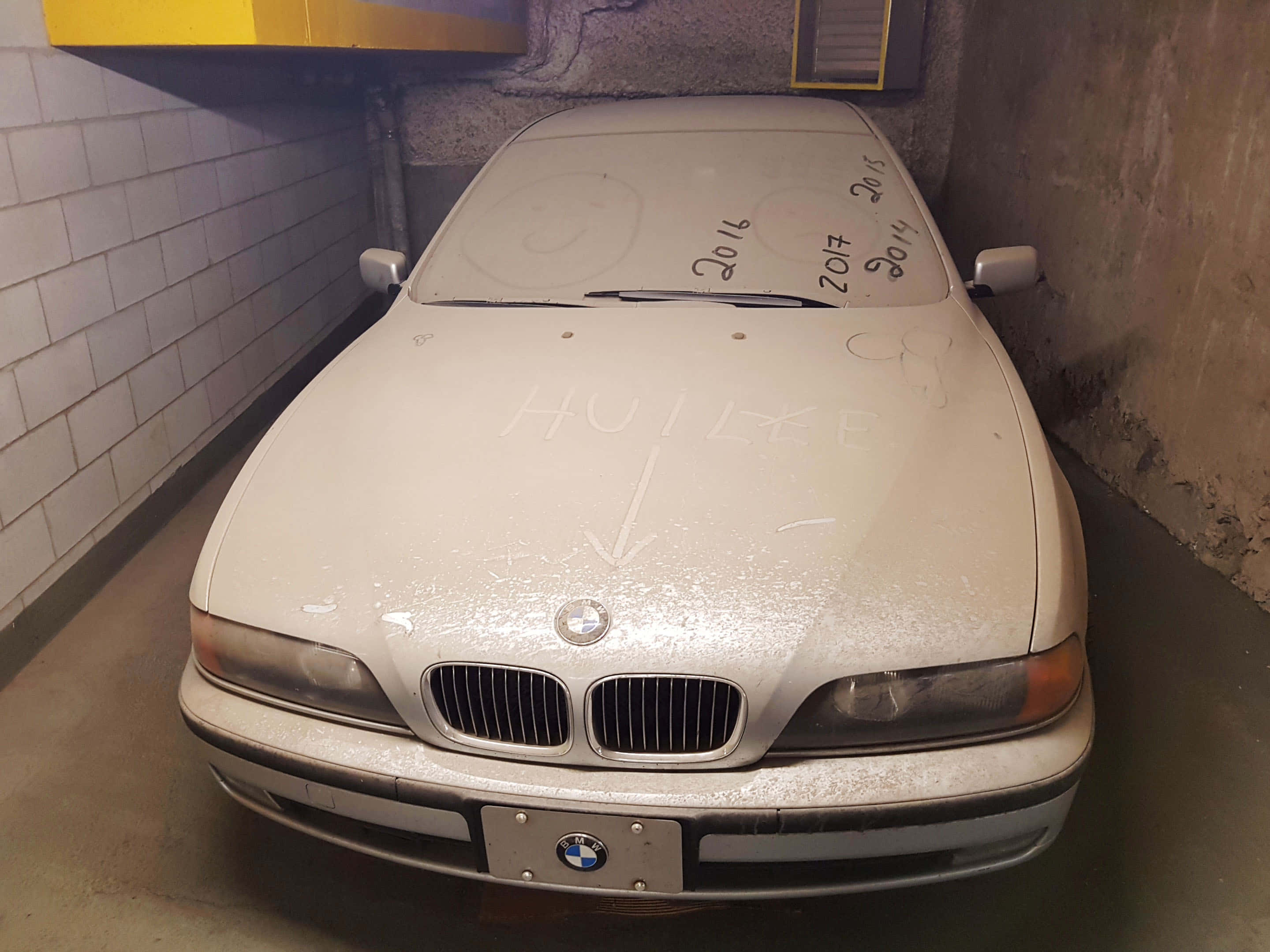 Dirty 桌布 壁紙 — 一輛佈滿灰塵的白色BMW轎車停放在昏暗的混凝土車庫中，引擎蓋上有塗鴉。