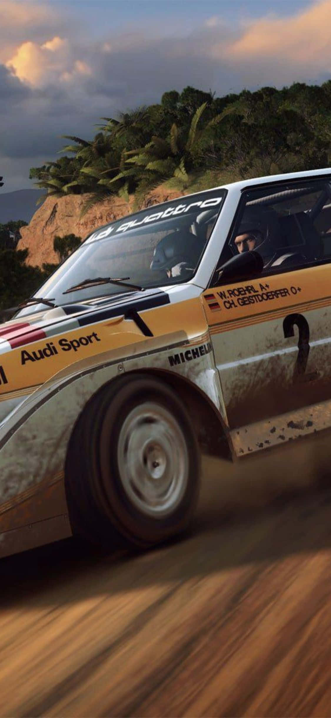 iPhone Xs Dirt Rally 桌布 壁紙 — 一輛佈滿灰塵的黃色奧迪拉力賽車在日落時分疾馳穿過熱帶森林峽谷。