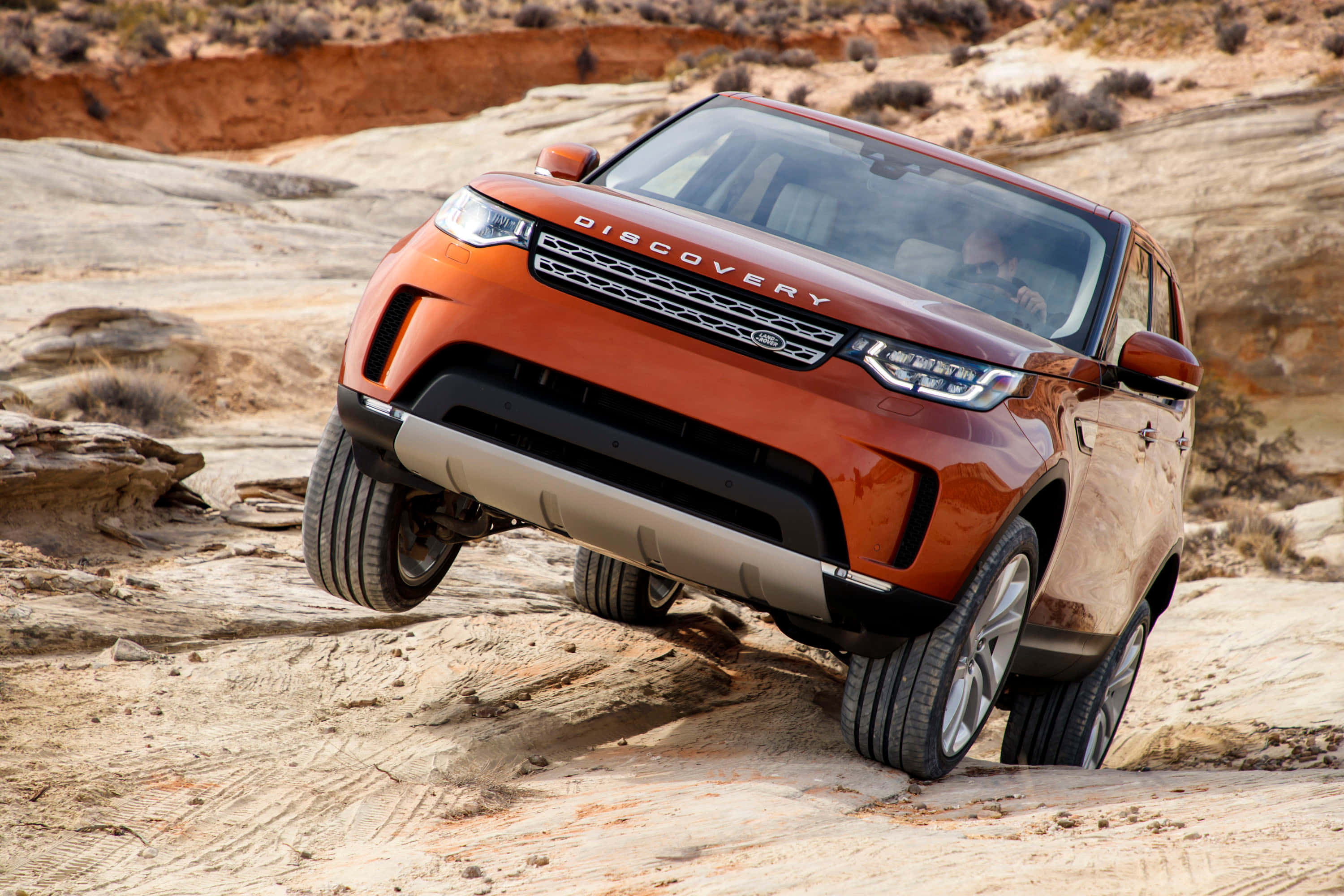 Land Rover Discovery 桌布 壁紙 — 一輛充滿活力的橙色 Land Rover Discovery 以大膽自信和粗獷優雅征服崎嶇的沙漠地形。