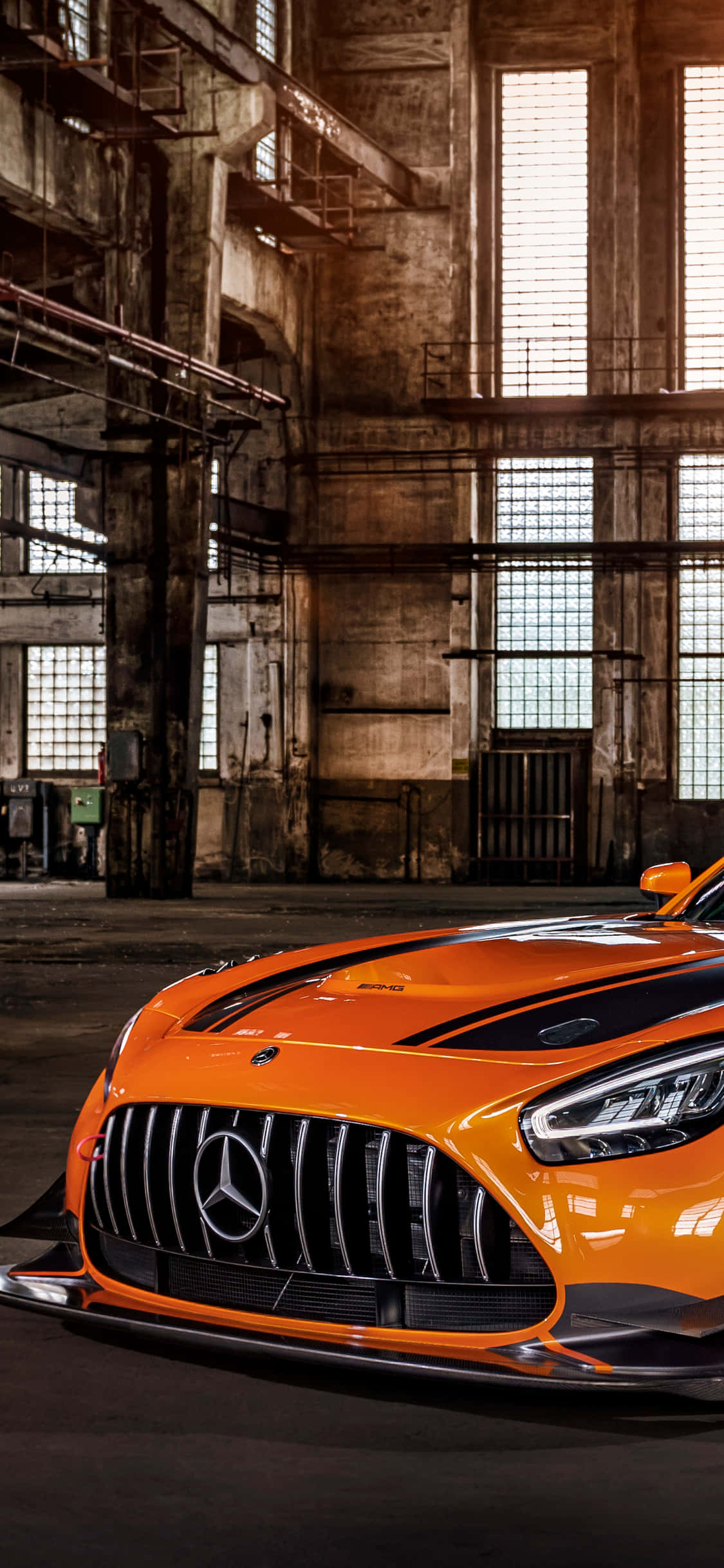 iPhone X Amg Gt-r 桌布 壁紙 — 一輛充滿活力的橙色 Mercedes-AMG GT R 跑車在破舊倉庫的工業天窗下閃閃發光。