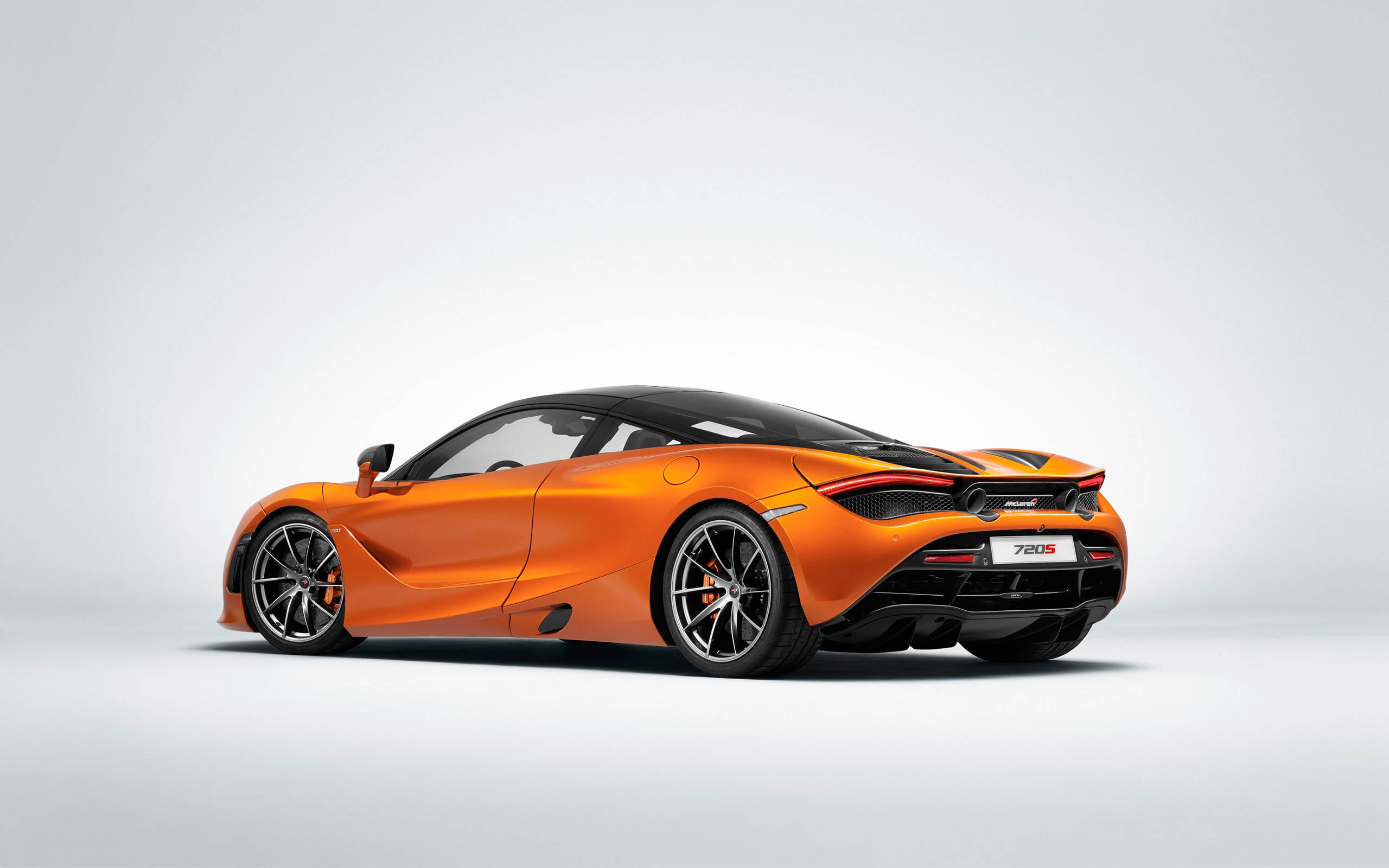 mclaren 720s 4K 桌布 壁紙 — 一輛充滿活力的橙色McLaren 720S跑車在簡約的攝影棚環境中展示，背景為純白色。