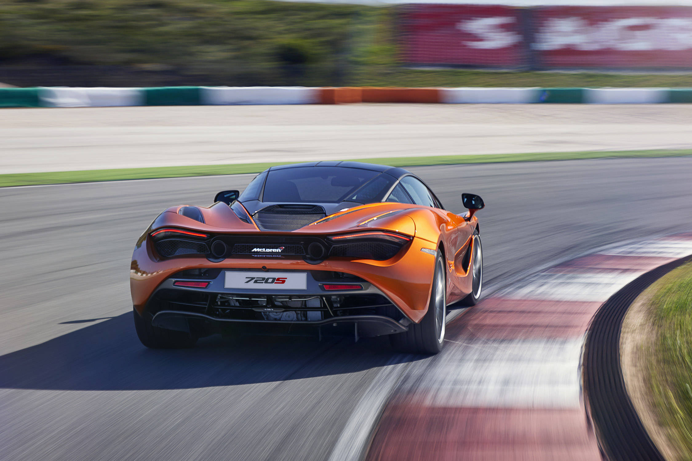 mclaren 720s 4K 桌布 壁紙 — 一輛充滿活力的橙色McLaren 720S在賽道彎角疾馳，動態模糊效果強調速度與精準。
