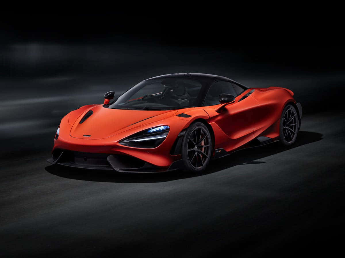 麥拉倫 桌布 壁紙 — 一輛充滿活力的橙色McLaren超級跑車在戲劇性的工作室燈光下，在黑暗陰鬱的背景中閃閃發光。