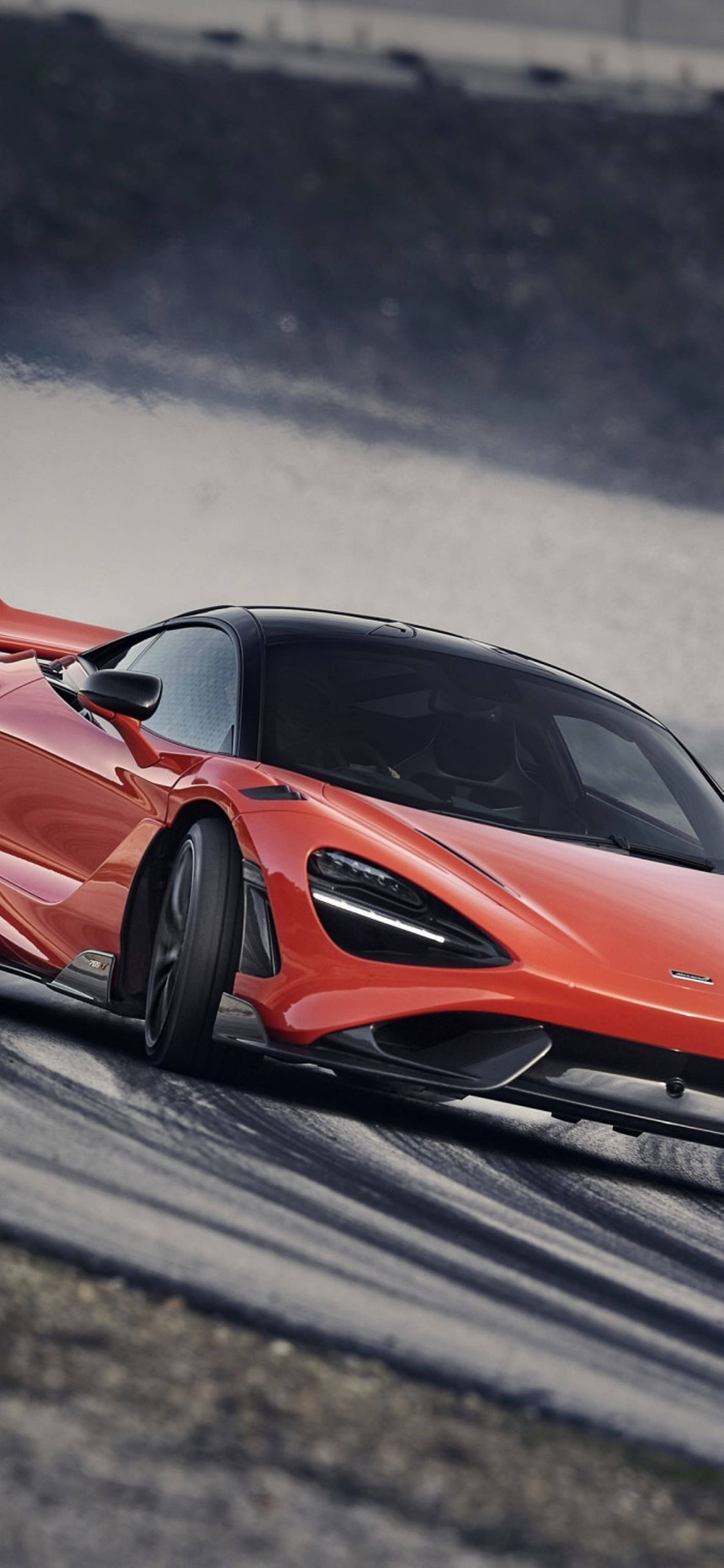 Luxury 桌布 壁紙 — 一輛充滿活力的橙色McLaren跑車在賽道上飄移，輪胎冒出滾滾濃煙。