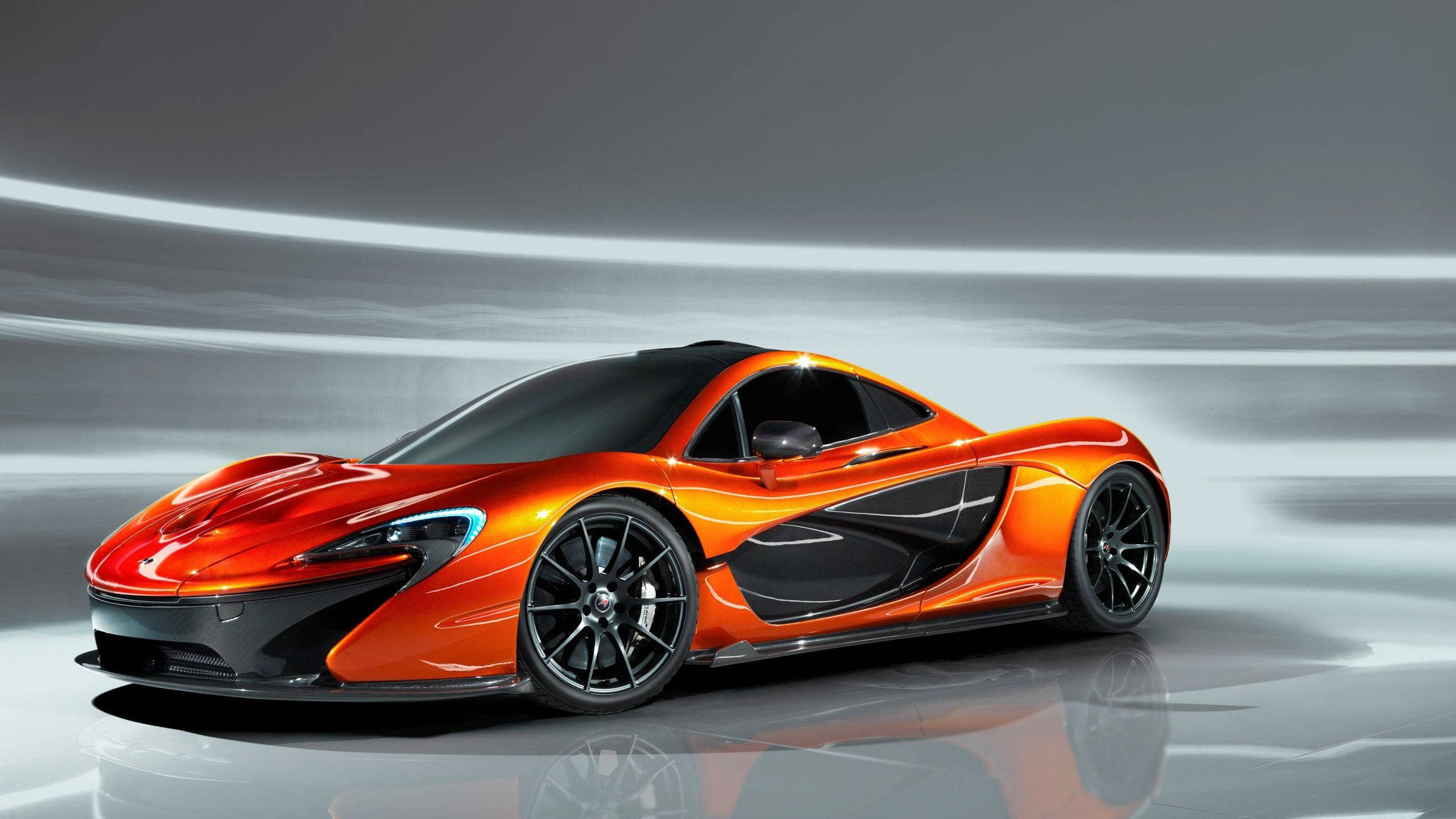 汽車 桌布 壁紙 — 一輛充滿活力的橙色McLaren P1超級跑車在攝影棚燈光下閃耀，背景是時尚的灰色動態模糊效果。