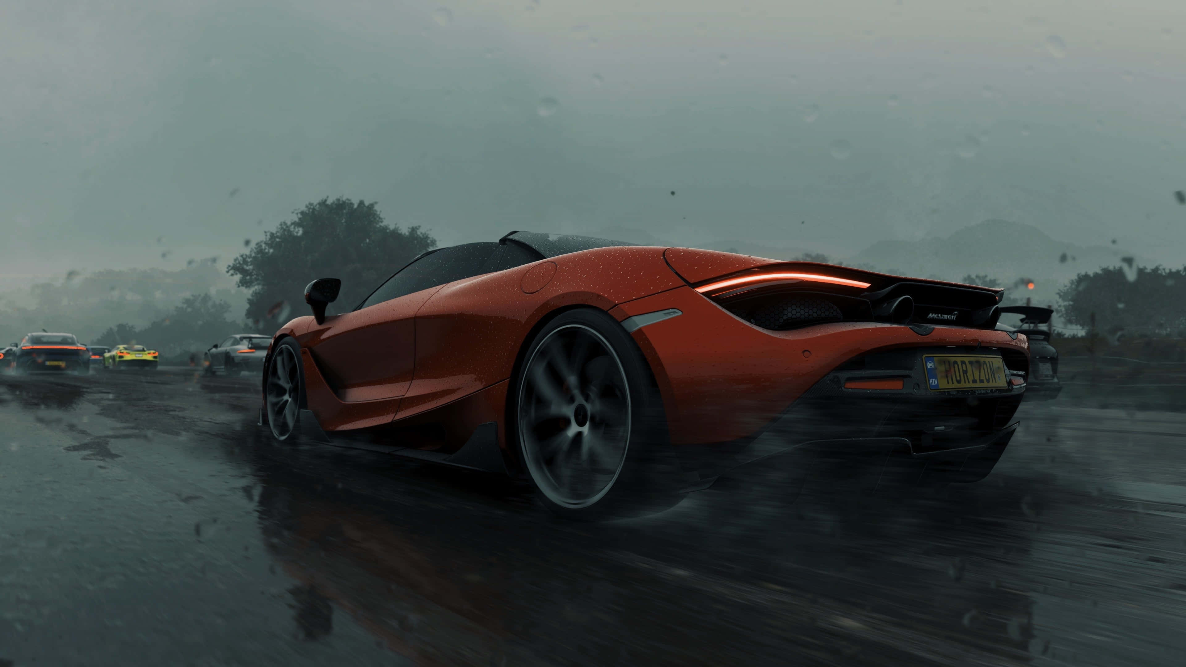 Forza Horizon 5 4K 桌布 壁紙 — 一輛充滿活力的橙色McLaren跑車在濕滑的賽道上飛馳，其他車輛在霧濛濛的背景中模糊不清。