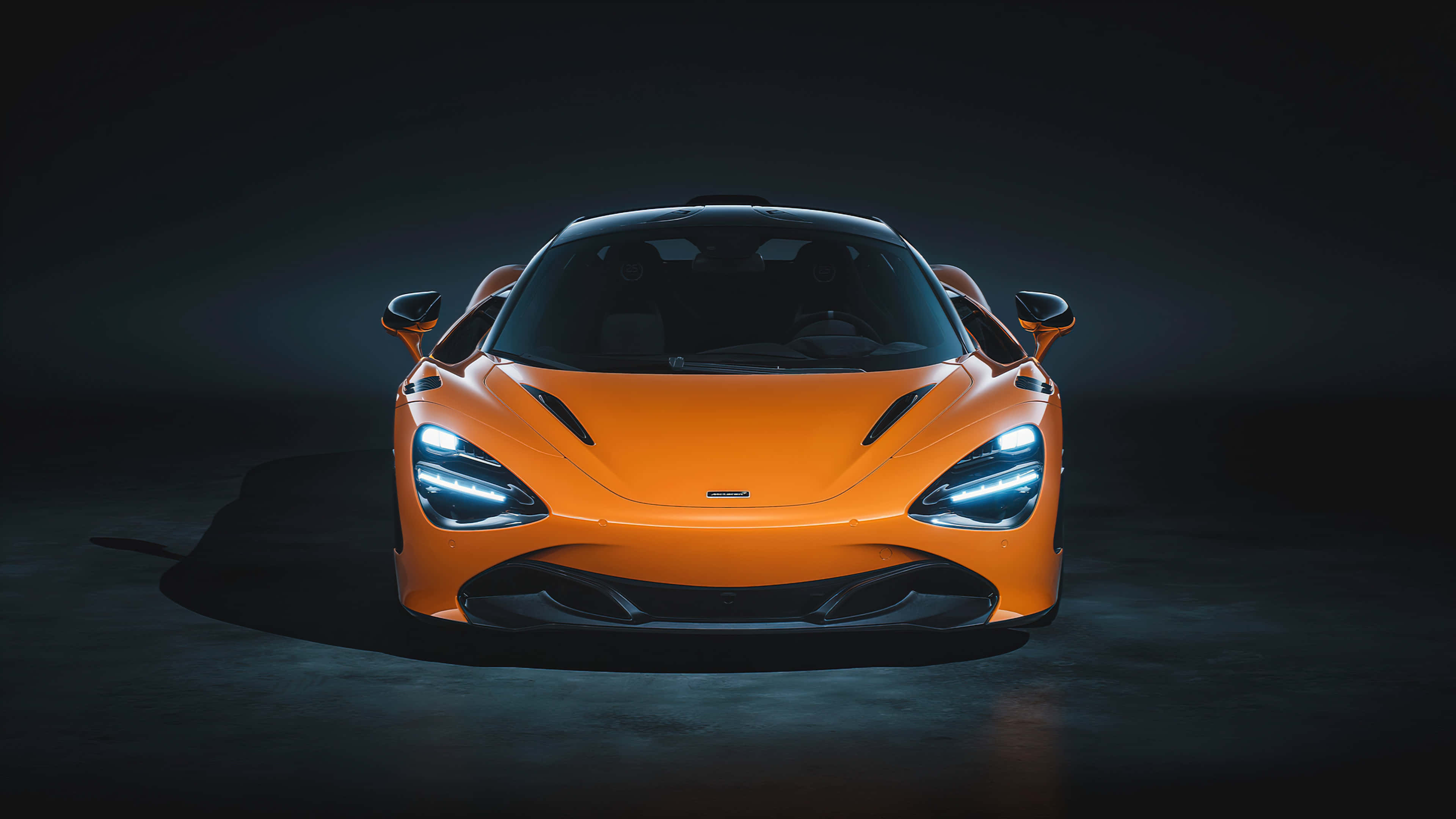 麥拉倫 桌布 壁紙 — 一輛充滿活力的橙色McLaren跑車在黑暗背景下，在戲劇性的工作室燈光下閃耀。