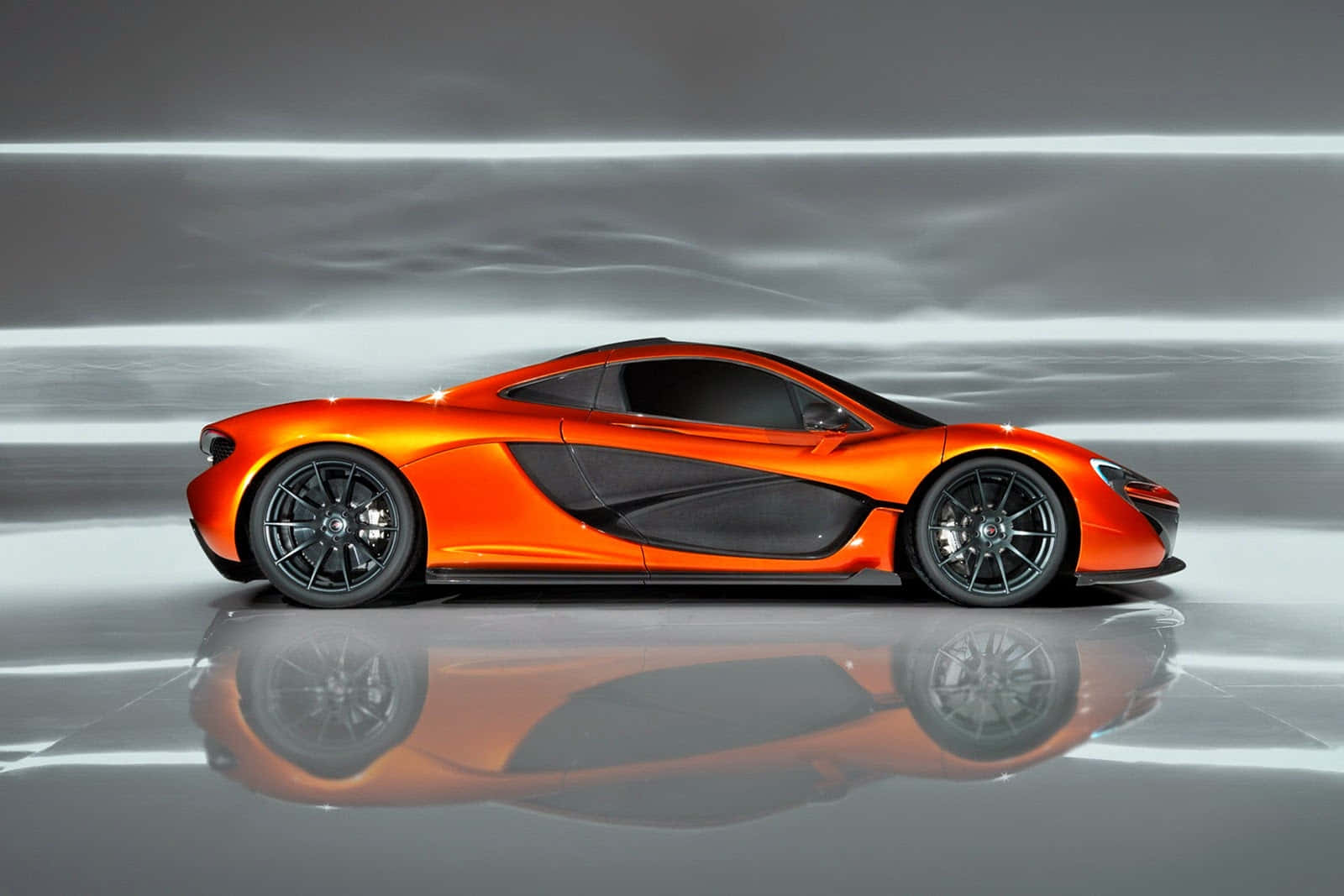 cars 桌布 壁紙 — 一輛充滿活力的橙色McLaren跑車在攝影棚燈光下閃閃發光，完美倒映在拋光地板上。