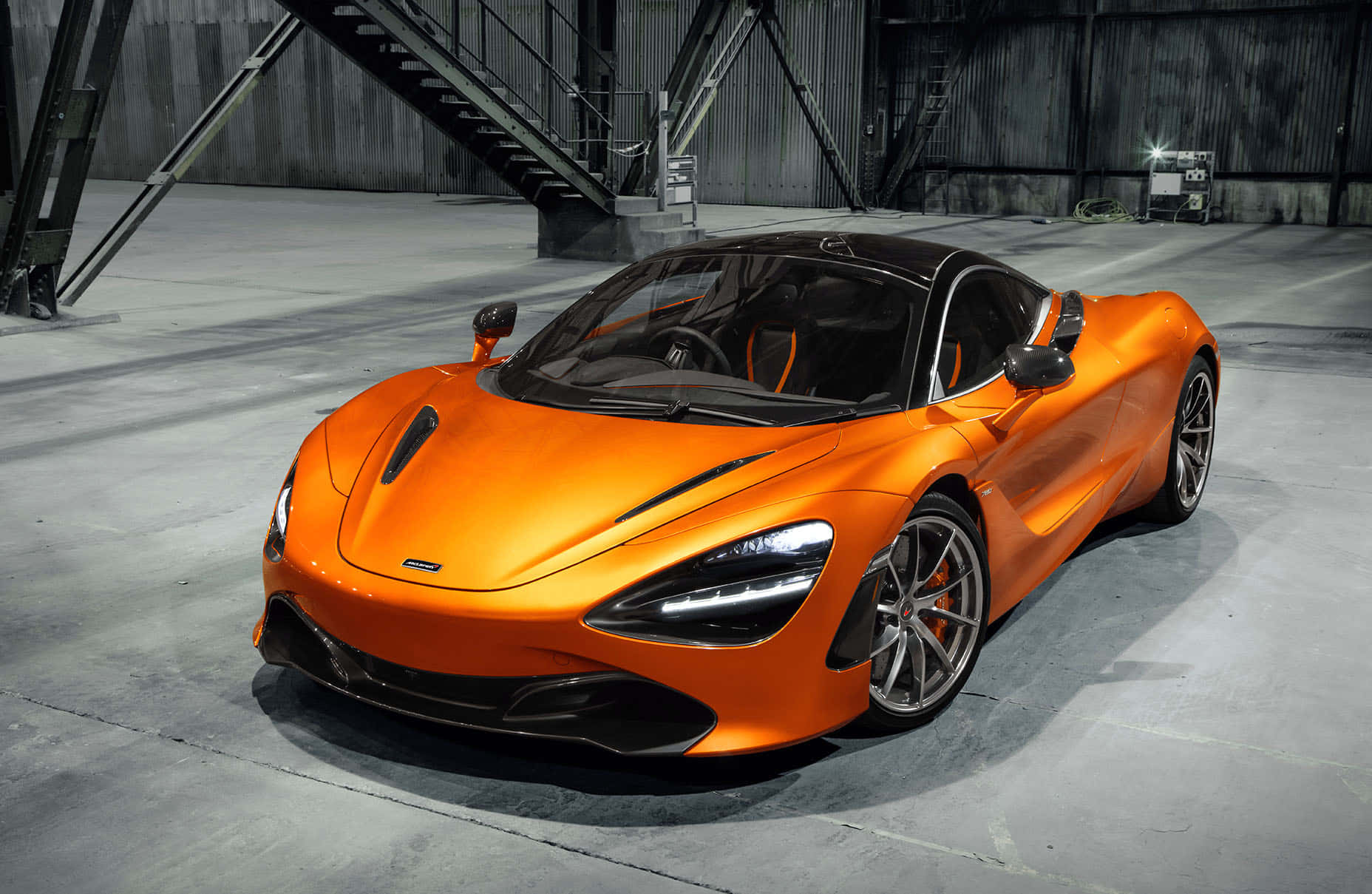 Warehouse 桌布 壁紙 — 一輛充滿活力的橙色McLaren 720S跑車在粗糙的工業倉庫中於攝影棚燈光下閃閃發光。