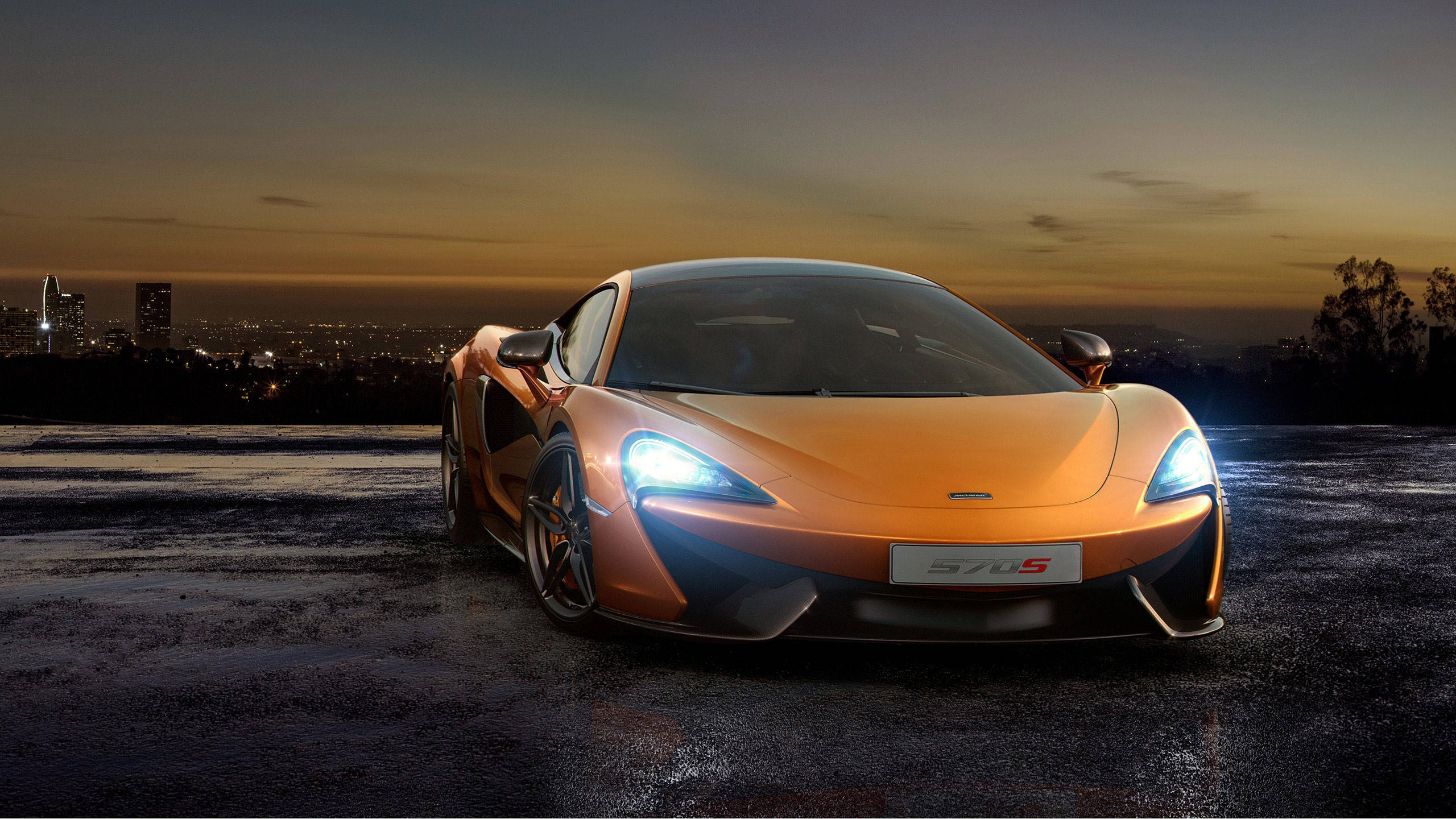 汽車 桌布 壁紙 — 一輛充滿活力的橙色McLaren 570S跑車在暮色中閃耀，背景中城市燈光閃爍。