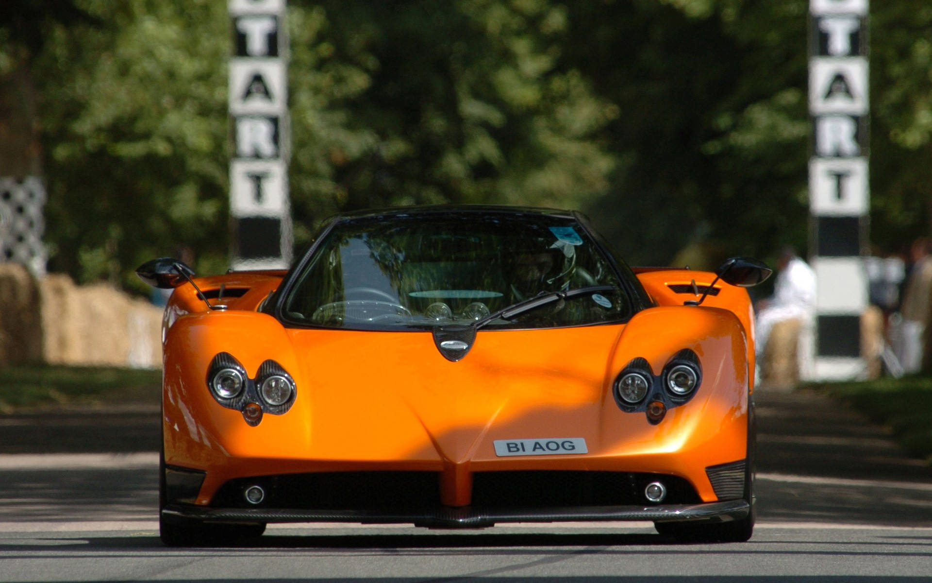 Pagani 桌布 壁紙 — 一輛充滿活力的橙色Pagani Zonda跑車在賽道上向前行駛，道路兩旁有「START」標誌。