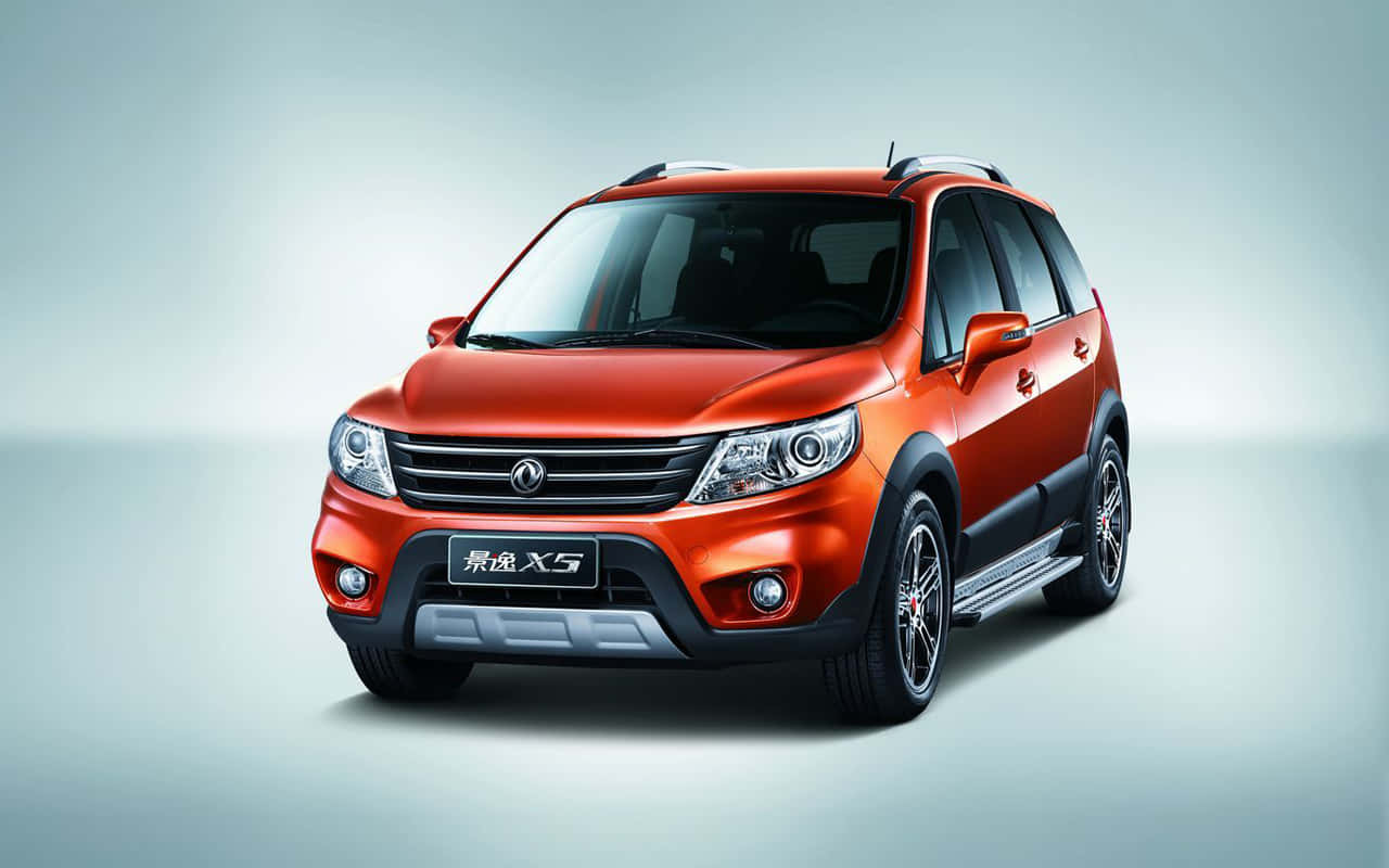 Dongfeng 桌布 壁紙 — 一輛充滿活力的橙色SUV，帶有黑色飾邊和銀色車頂行李架，在柔和的漸變工作室背景前展示。