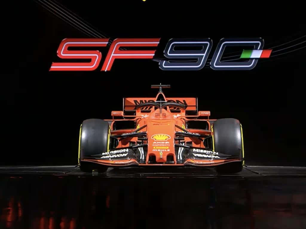 Racing 桌布 壁紙 — 一輛充滿活力的橙色一級方程式賽車SF90在黑暗的舞台上展示，上方有發光的標誌，燈光效果戲劇化。