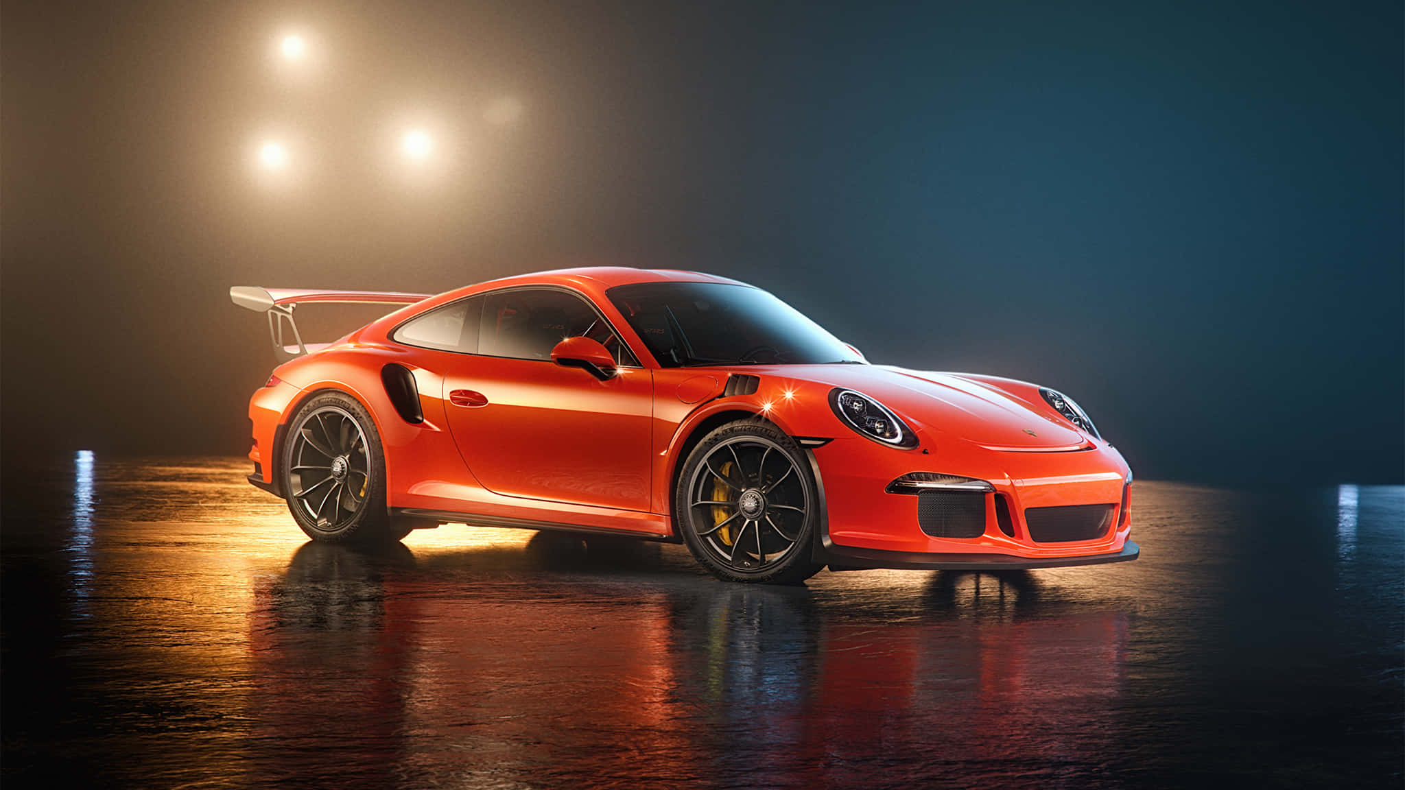 保時捷 桌布 壁紙 — 一輛充滿活力的橙色保時捷911 GT2 RS在黑暗工作室的潮濕反光地板上，在戲劇性的聚光燈下閃閃發光。