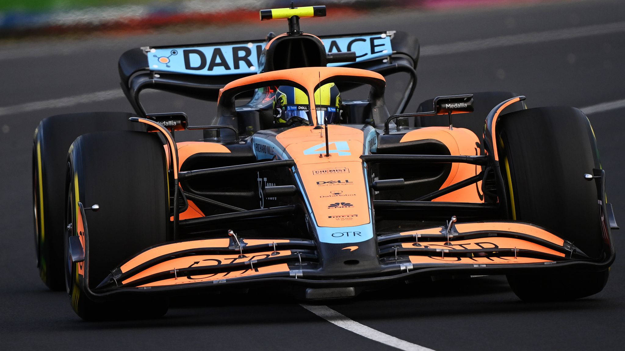 Racing 桌布 壁紙 — 一輛充滿活力的橙色和黑色一級方程式賽車在賽道上疾馳，車手戴著頭盔清晰可見。