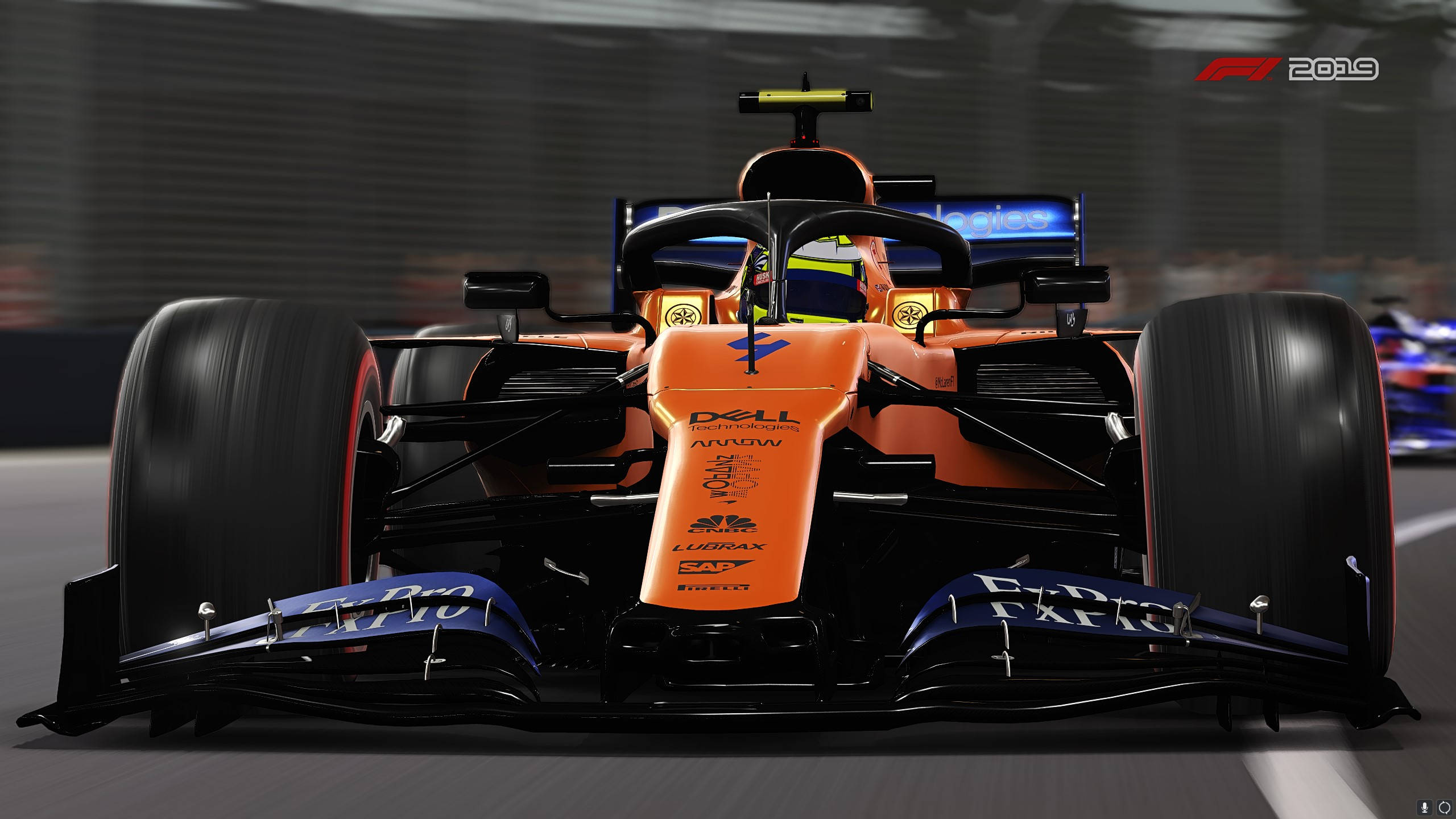 F1 2019 壁紙 桌布 壁紙 — 一輛充滿活力的橙色和黑色一級方程式賽車在賽道上疾馳，帶有模糊的動感和可見的贊助商標誌。