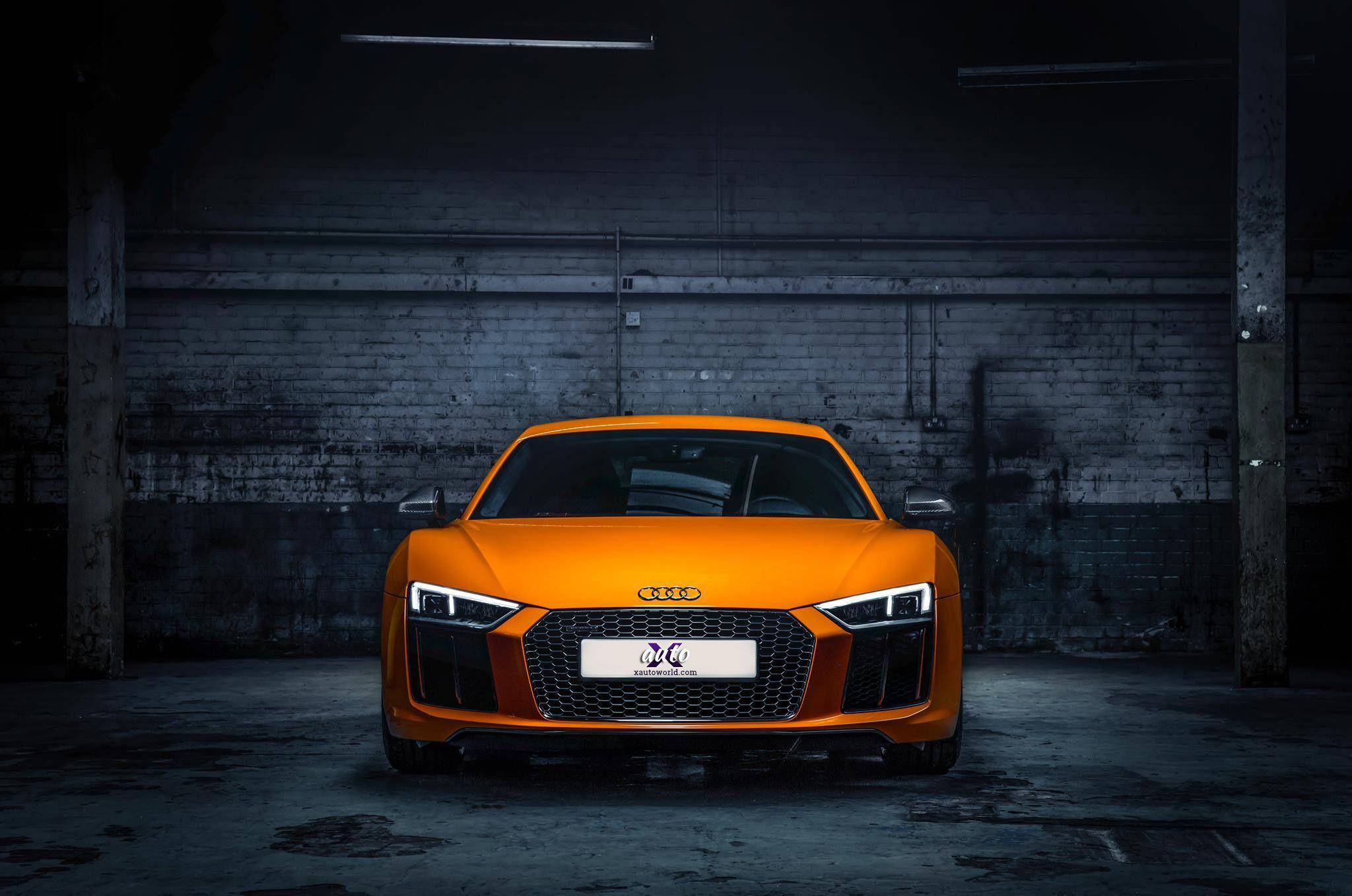 R8 桌布 壁紙 — 一輛充滿活力的橙色奧迪R8跑車在昏暗骯髒的工業倉庫中，於聚焦燈光下閃閃發光。