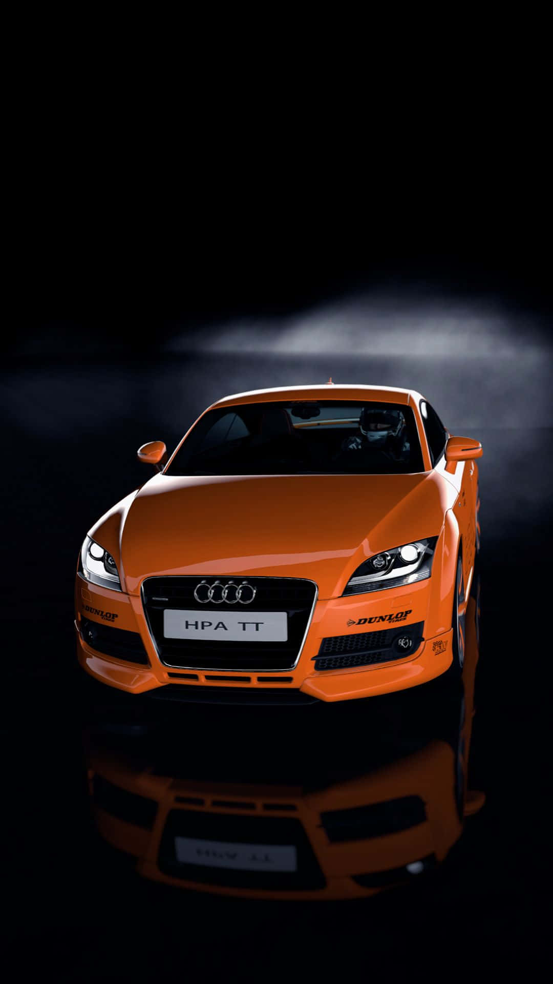 Audi Tt 桌布 壁紙 — 一輛充滿活力的橙色奧迪TT賽車在戲劇性的攝影棚燈光下，在帶有反射表面的黑色背景前閃閃發光。