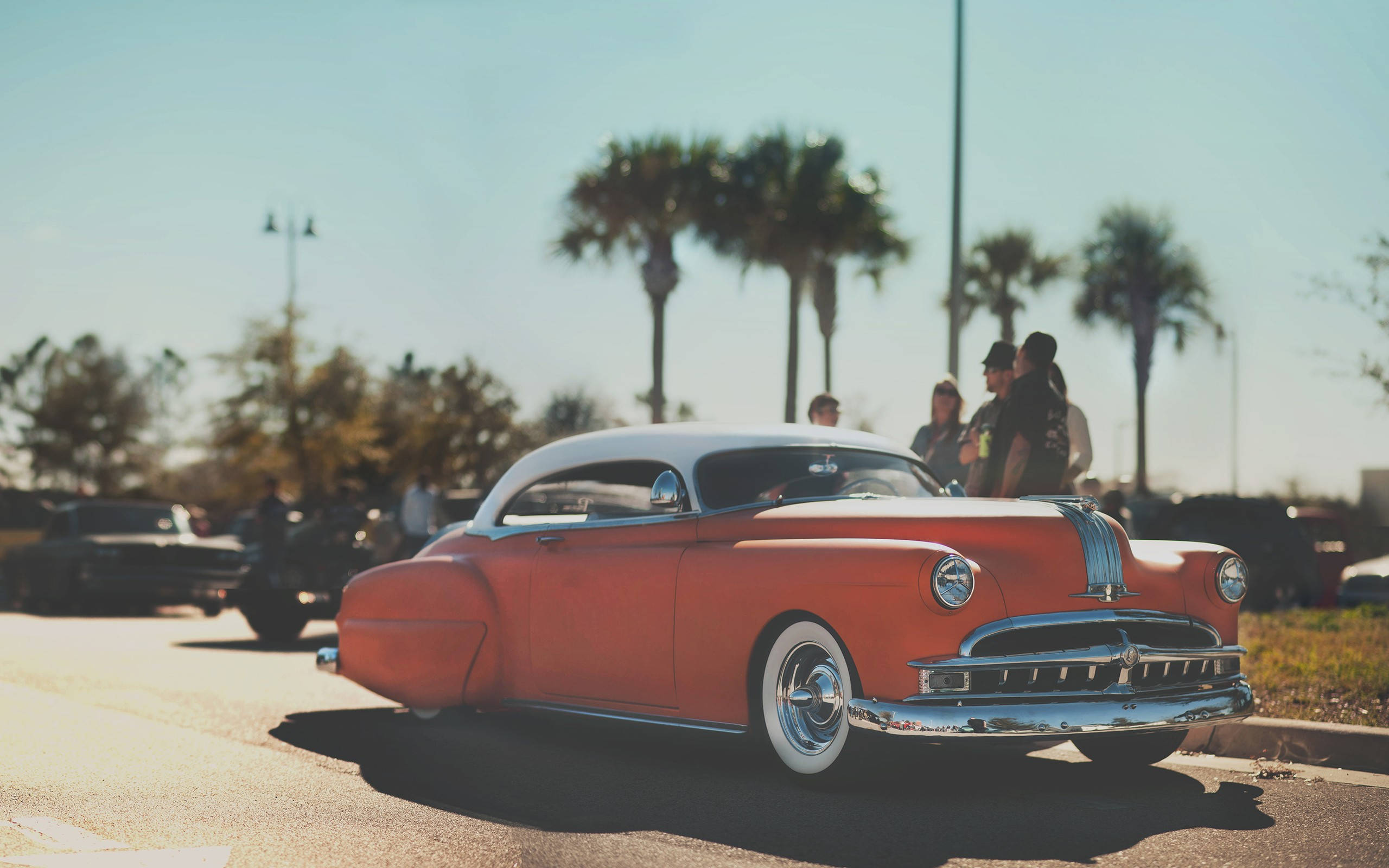 Pontiac 桌布 壁紙 — 一輛充滿活力的橙色復古車，帶有鍍鉻裝飾，停在陽光明媚、棕櫚樹成蔭的街道上。