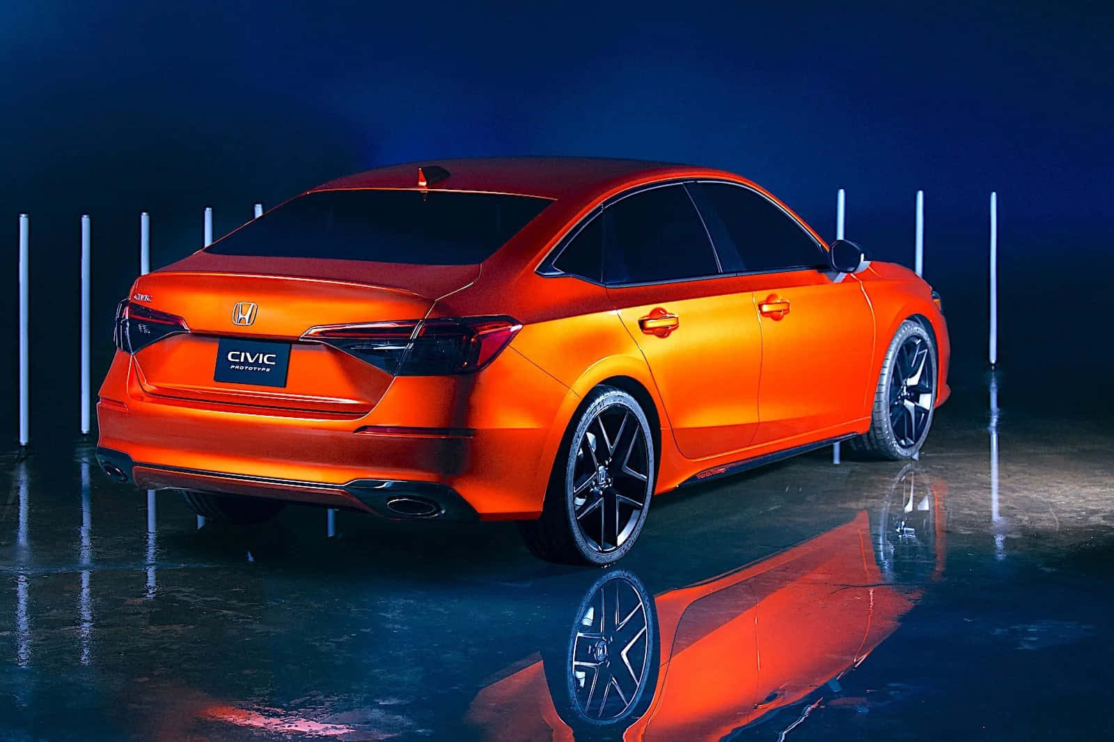 Honda Civic 桌布 壁紙 — 一輛充滿活力的橙色本田思域轎車在戲劇性的藍色燈光下閃閃發光，並在潮濕的攝影棚地板上反射出倒影。