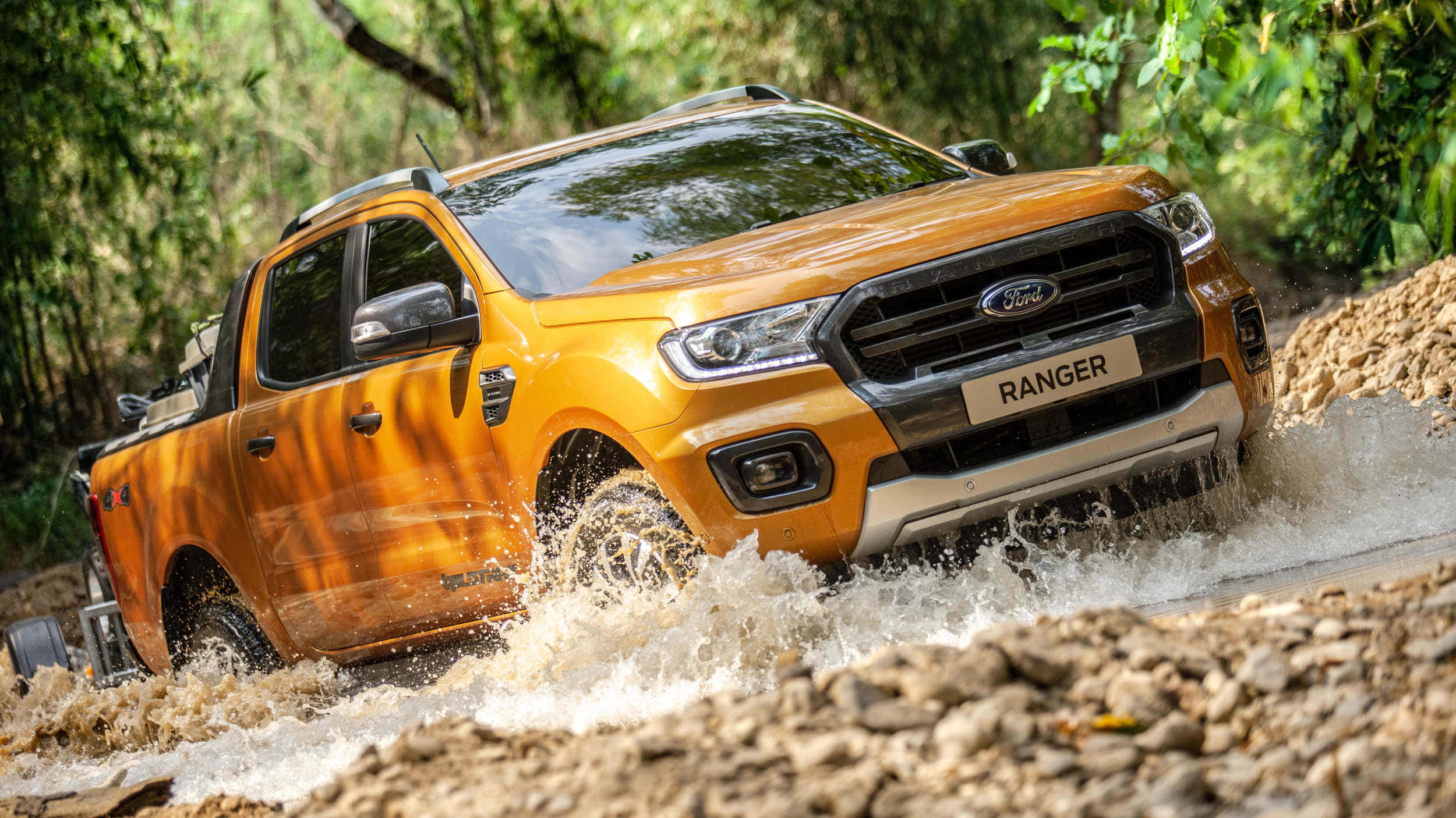 Ford Truck 桌布 壁紙 — 一輛充滿活力的橙色福特 Ranger 皮卡車在泥濘的森林溪流中飛馳，水花四濺。