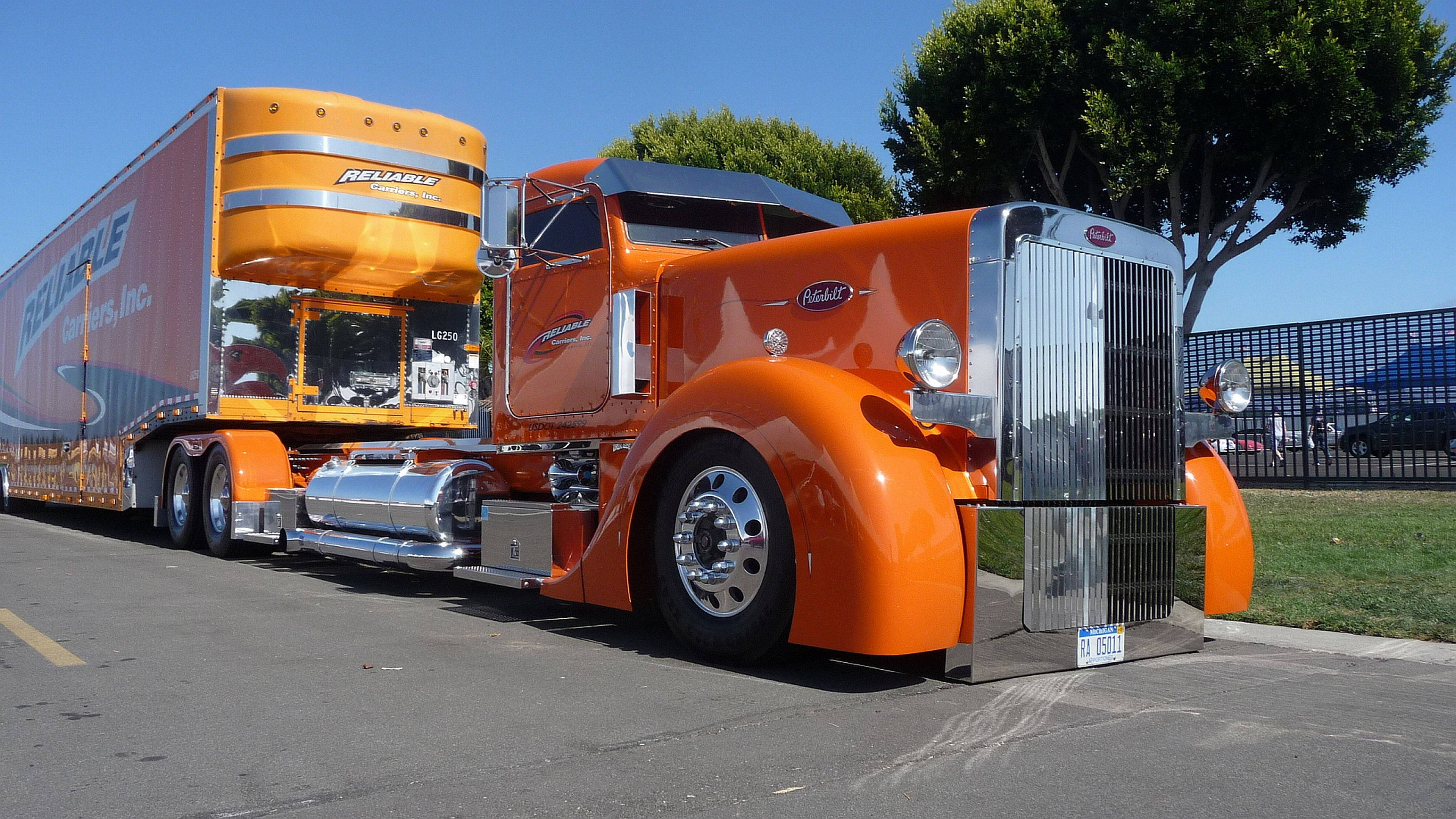 Trucks 桌布 壁紙 — 一輛充滿活力的橙色經典半掛卡車，帶有鍍鉻裝飾和匹配的拖車，停在清澈的藍天下。