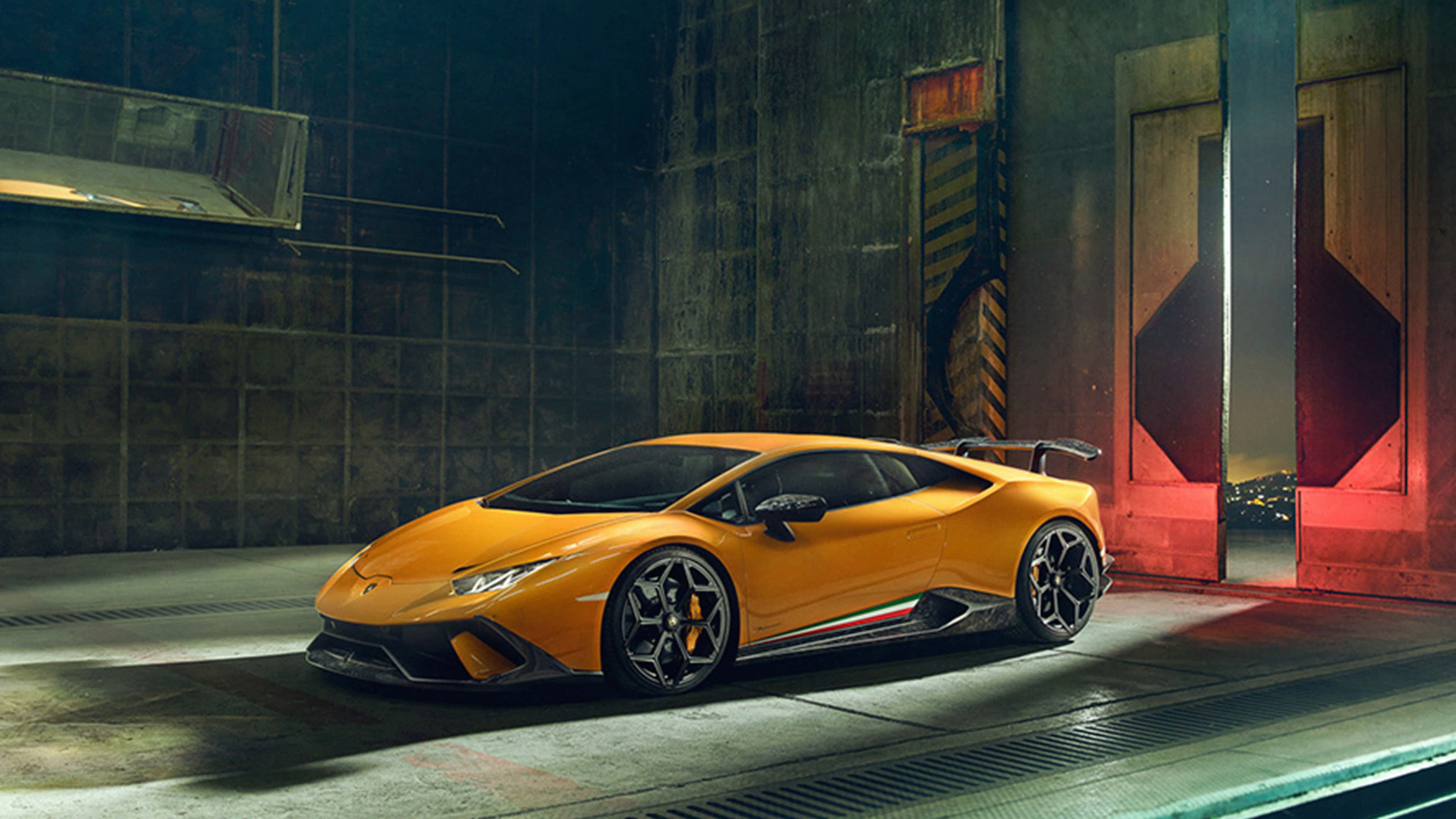 桌布 壁紙 — 一輛充滿活力的橙色藍寶堅尼 Huracán Performante 在骯髒的工業車庫中，在戲劇性的燈光下閃閃發光。