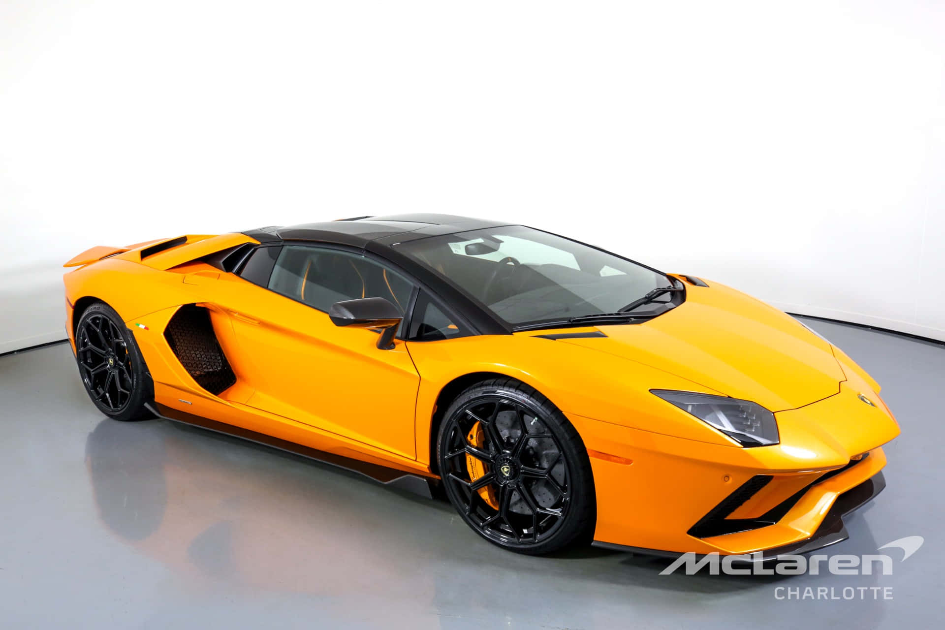 Lamborghini Aventador 桌布 壁紙 — 一輛充滿活力的橙色藍寶堅尼Aventador，帶有黑色飾邊和車輪，在簡約的工作室環境中展示。