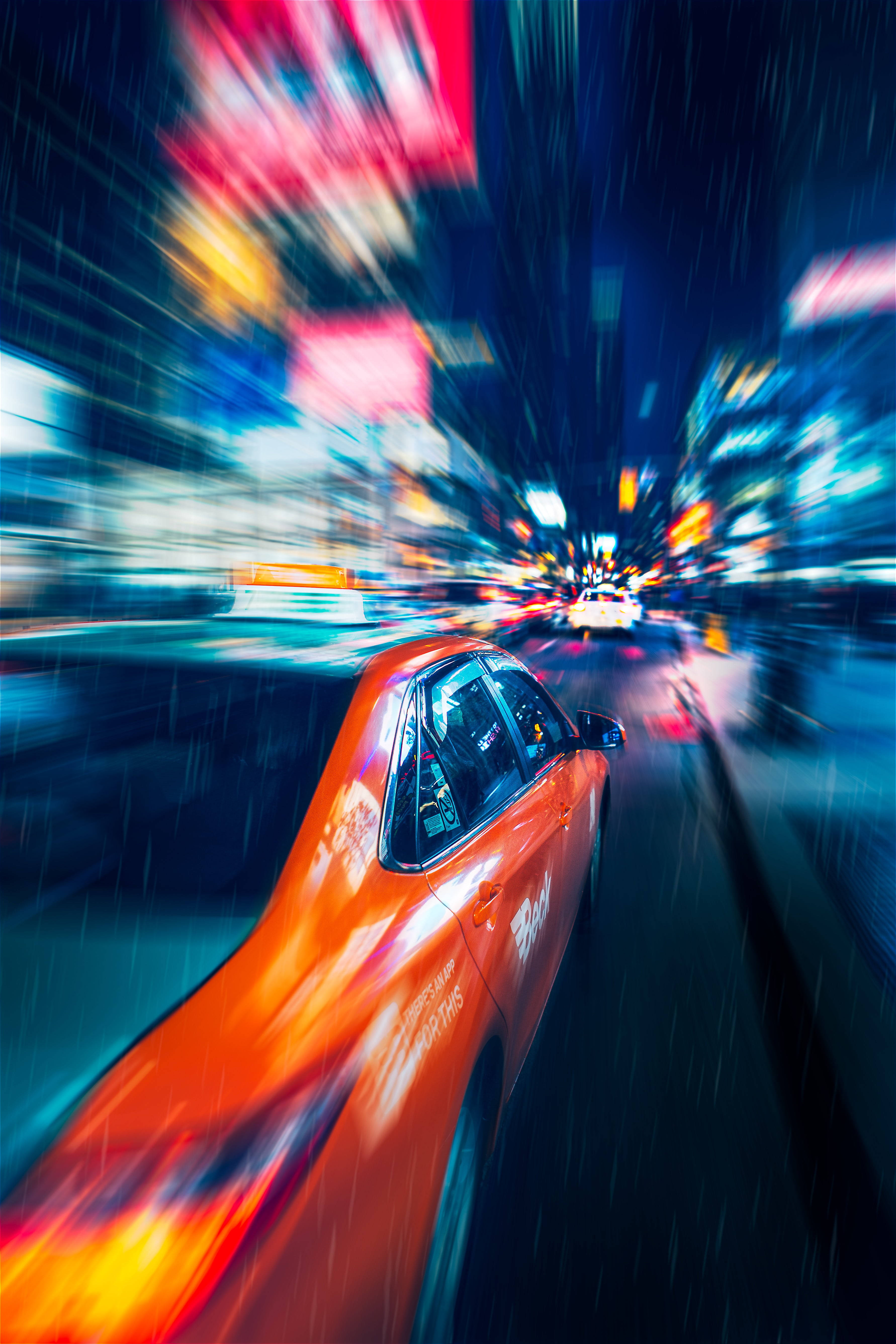 speeding car 桌布 壁紙 — 一輛充滿活力的橙色計程車在夜間穿過濕漉漉的霓虹城市，其速度產生的動態模糊向外輻射。