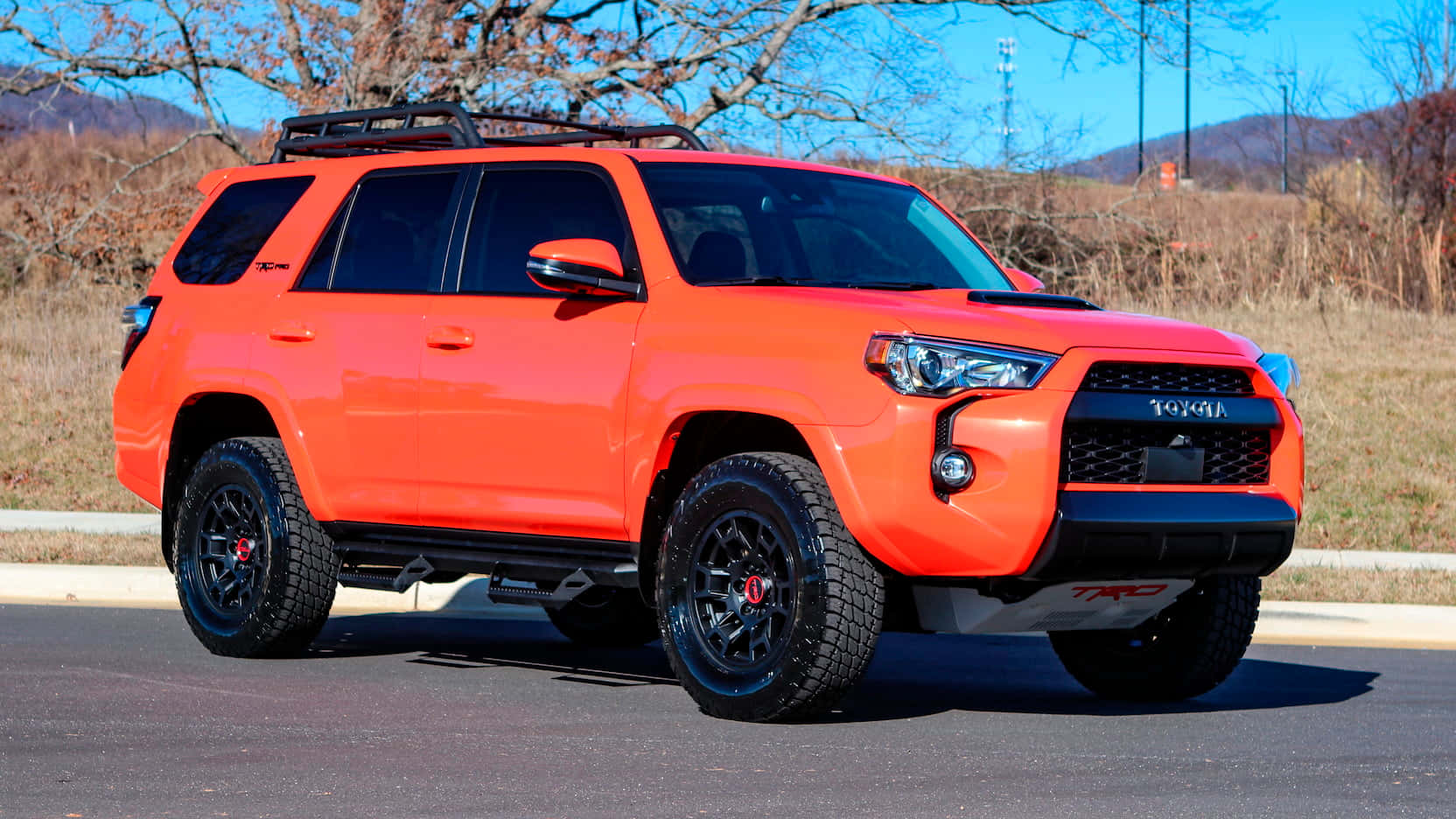 明亮的橙色豐田 4Runner TRD 停放在路上，背景是山脈。 — Toyota Supra Mk4 壁紙