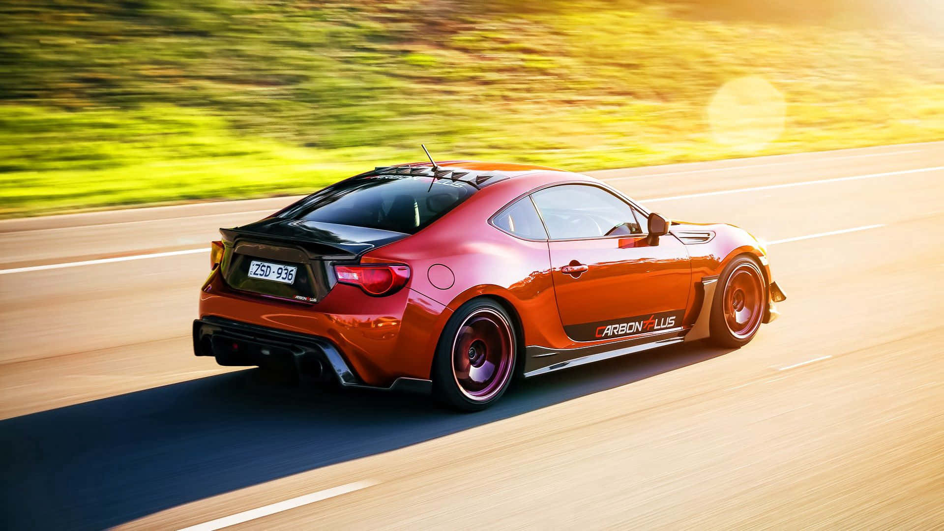 橙色跑車在陽光明媚的道路上奔馳，帶有動態模糊效果。 — Toyota Supra Mk4 壁紙
