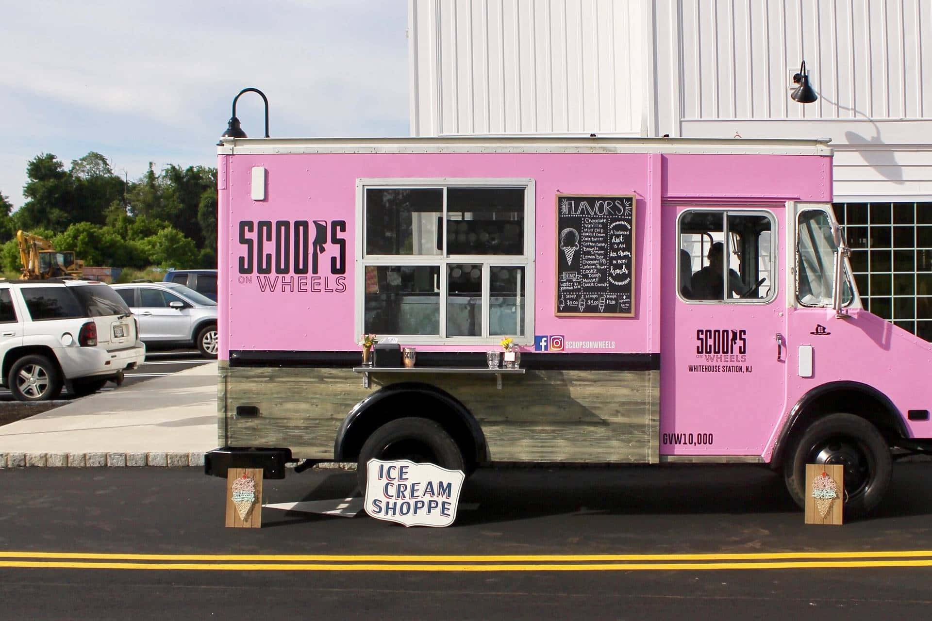 Ice Cream Truck 桌布 壁紙 — 一輛充滿活力的粉紅色冰淇淋車停泊在陽光明媚的街道上，設有黑板菜單和「ICE CREAM SHOPPE」標誌。