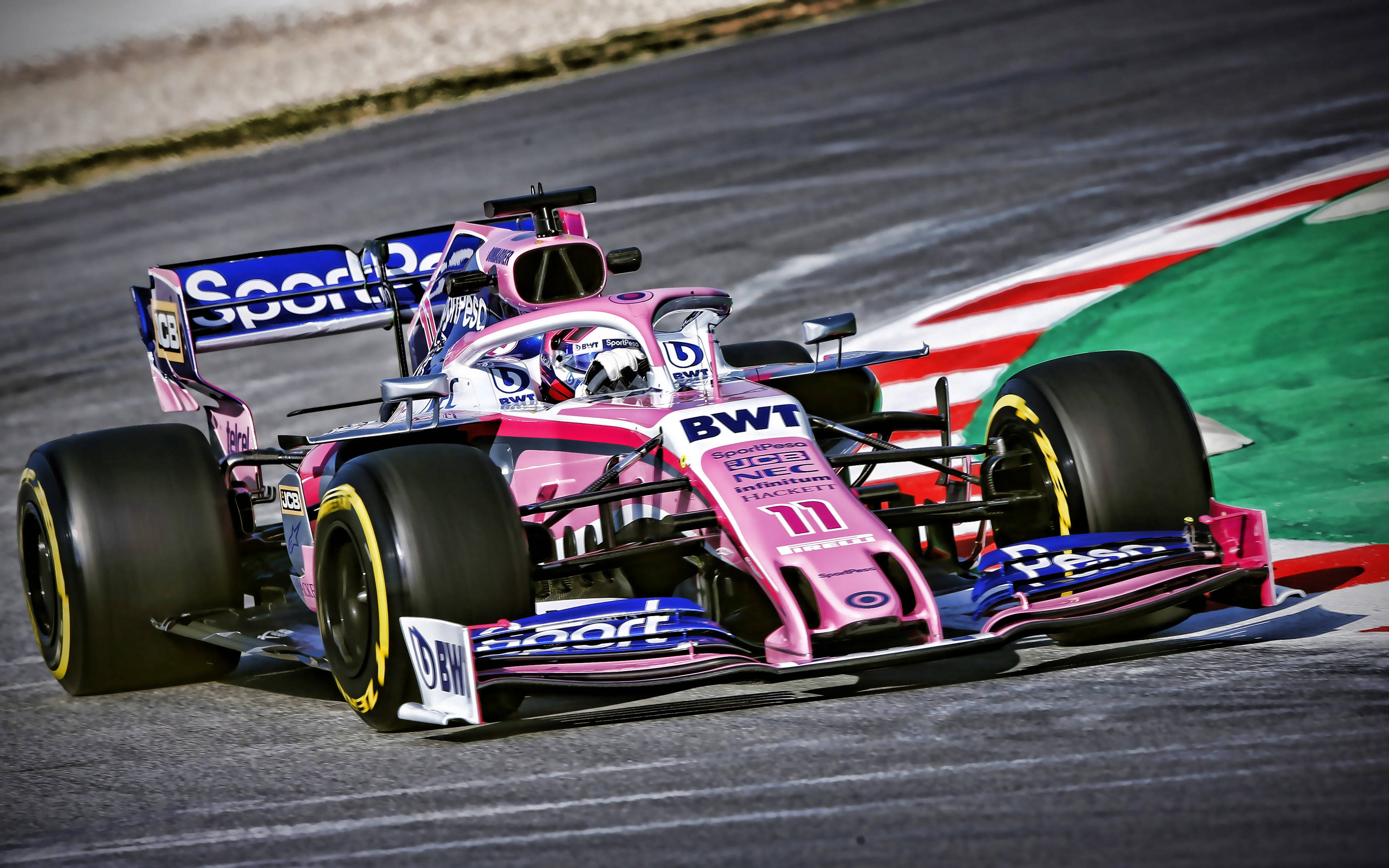 sergio perez 桌布 壁紙 — 一輛充滿活力的粉紅色和藍色一級方程式賽車在賽道彎道上疾馳，彎道有紅色、白色和綠色的路緣石。