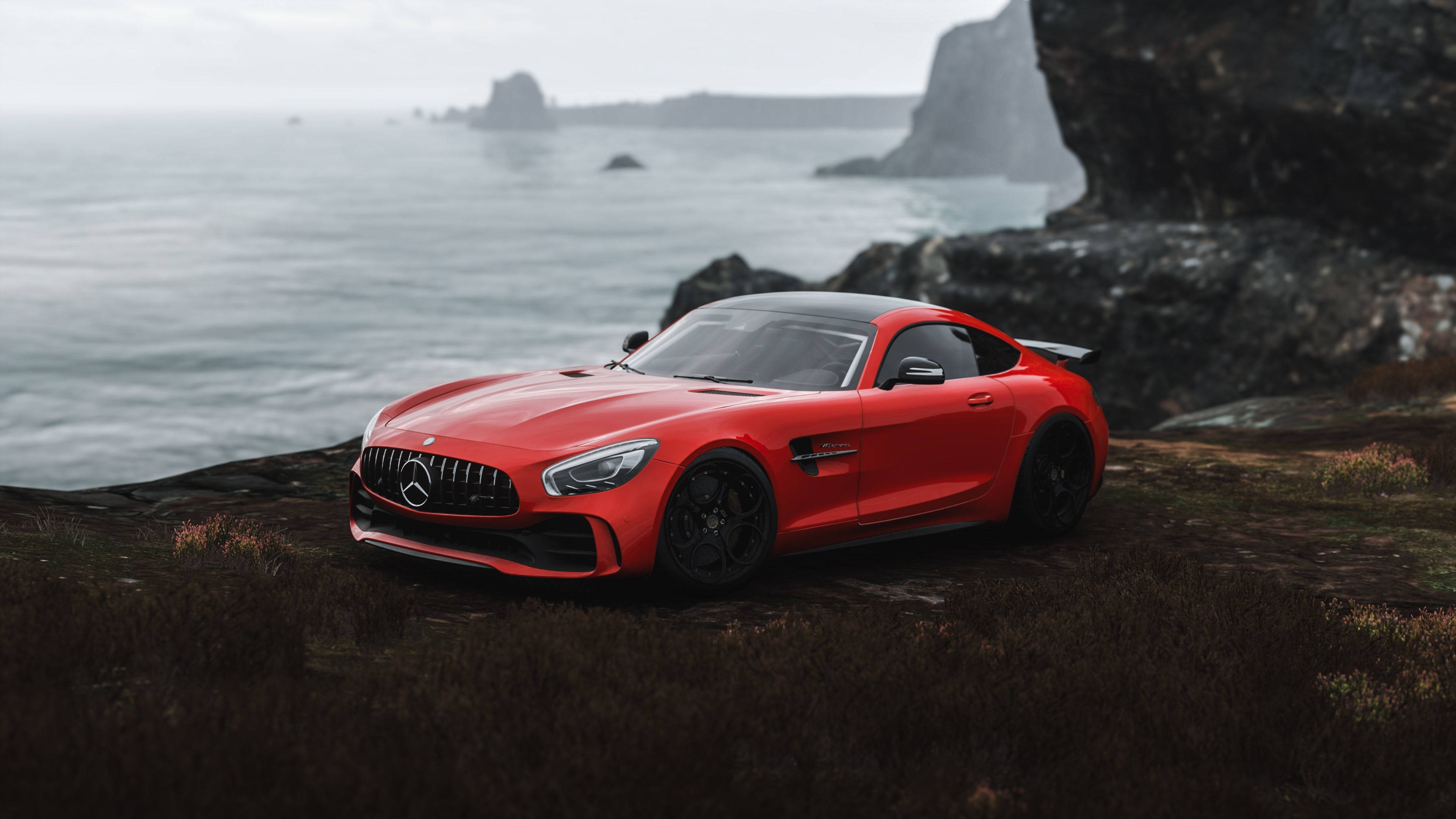 Mercedes 桌布 壁紙 — 一輛充滿活力的紅色 Mercedes-AMG GT 停泊在崎嶇的懸崖上，俯瞰著霧氣瀰漫的海洋和岩石露頭。